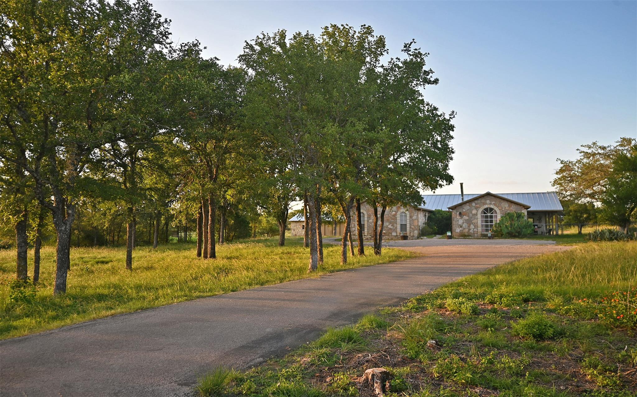 Mature trees frame the paved approach to this rus