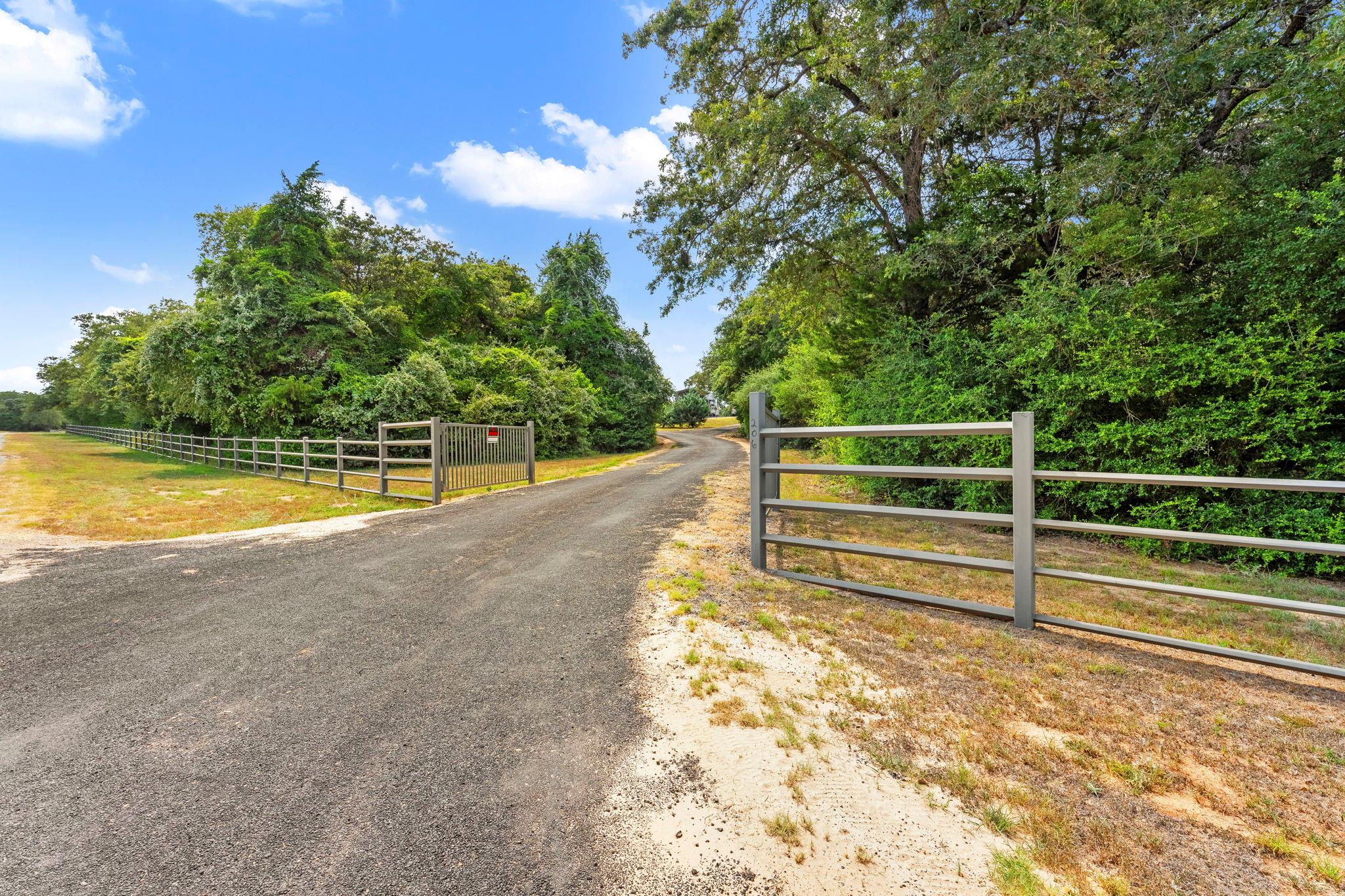 A secured gated entry leads down a long driveway 