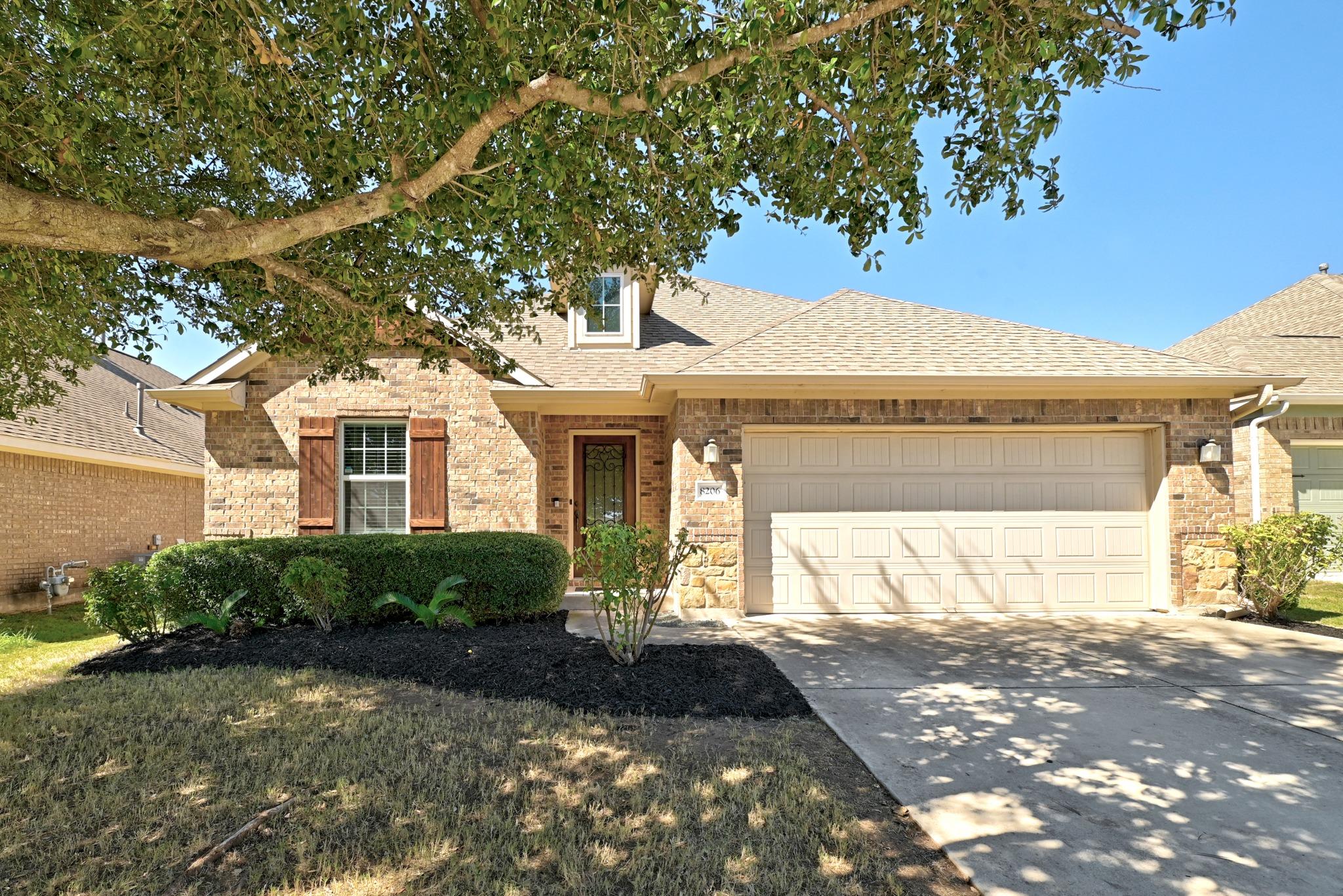 Mature trees shade a classic brick exterior compl