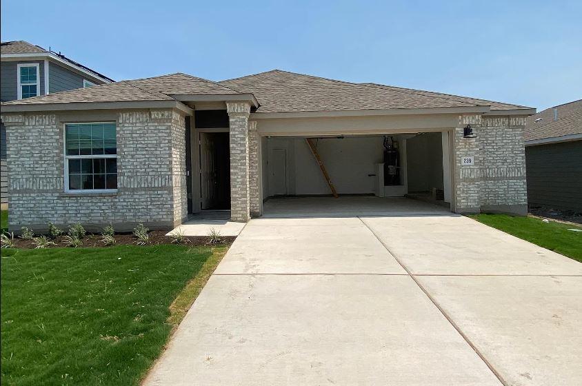 A well-maintained lawn and concrete driveway lead