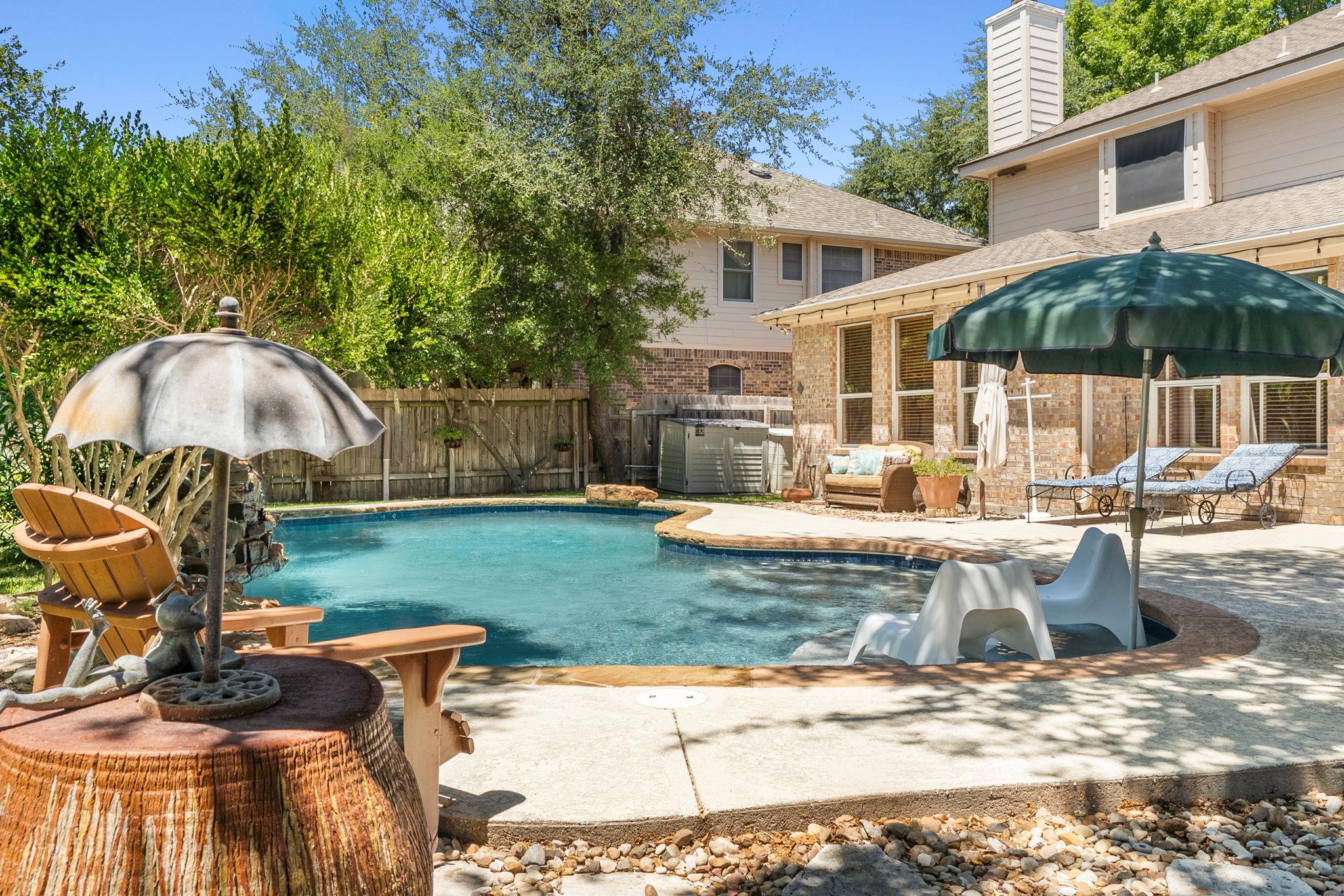 Mature trees frame a concrete patio surrounding t