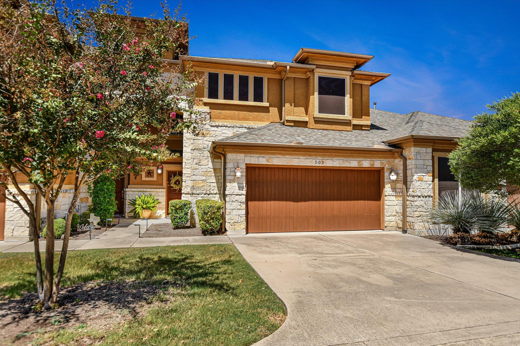 Natural stone accents and a wide concrete drivewa