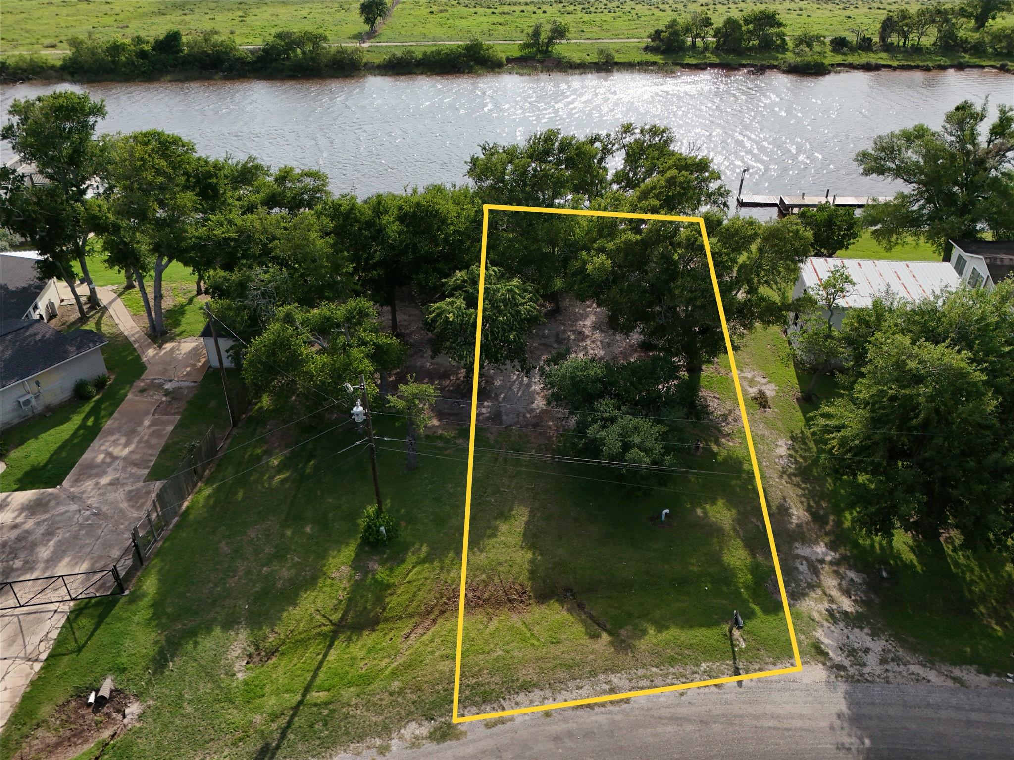Mature trees frame this grassy waterfront parcel 
