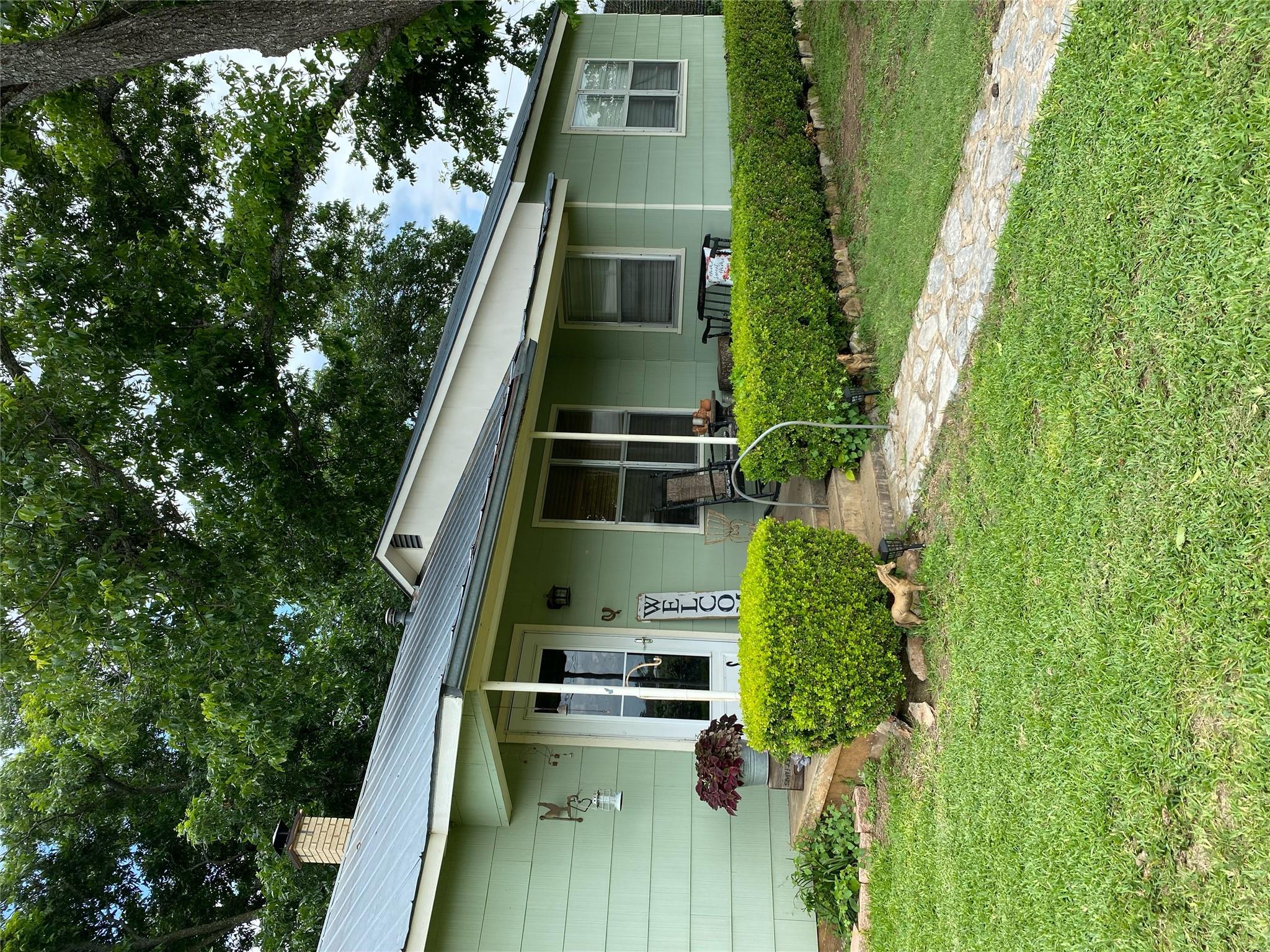 Mature trees shade a welcoming front porch with c