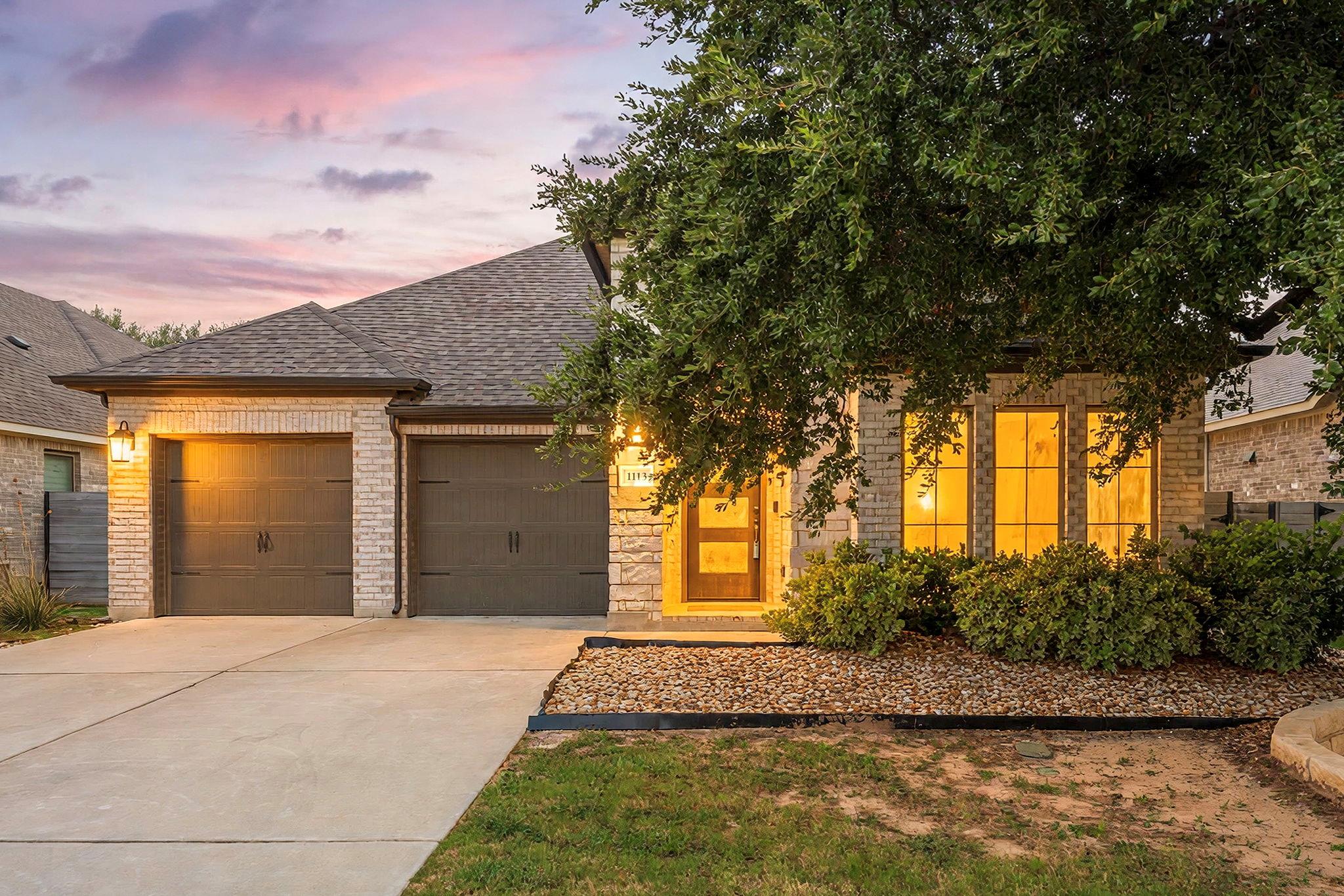 A classic brick exterior sits framed by mature sh