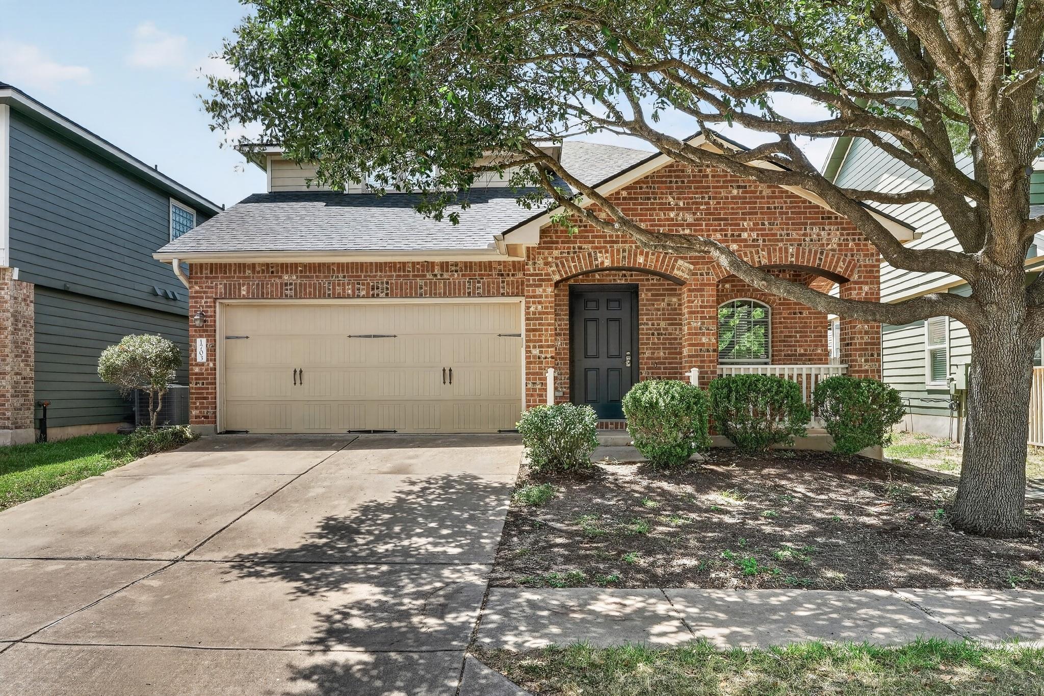 Mature shade trees frame a classic brick facade f