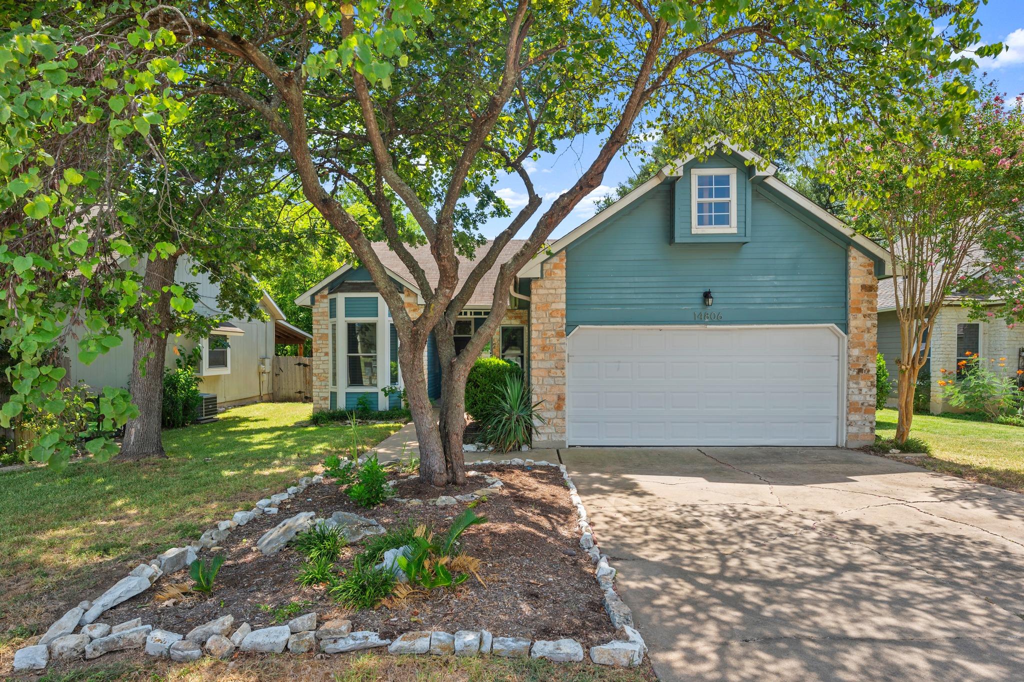 Mature trees shade the driveway and front facade 