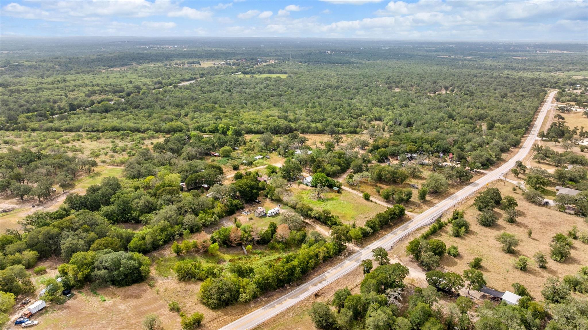 Dense woodlands and open pastures border a paved 