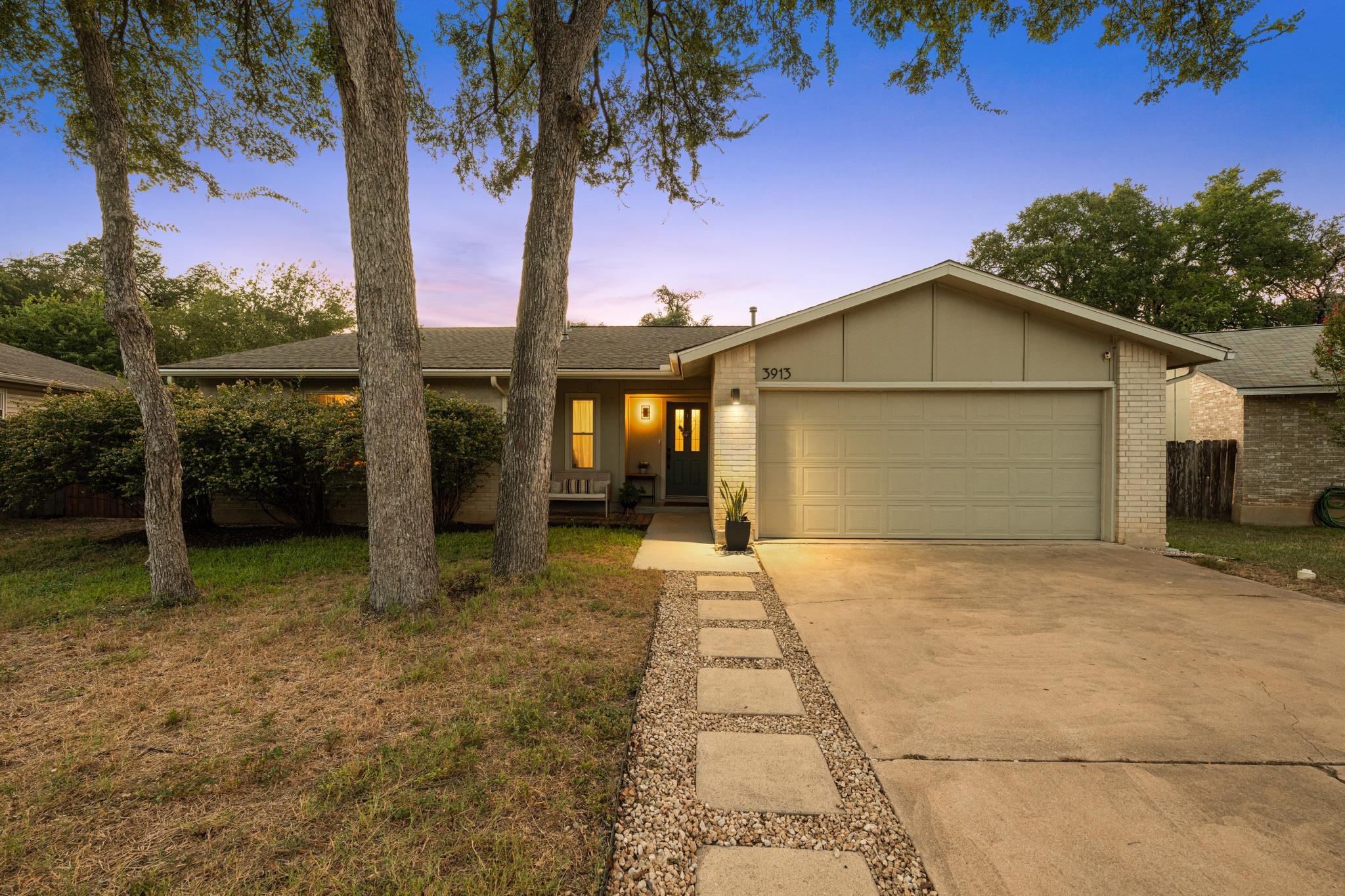 Mature trees frame the front elevation of this cl