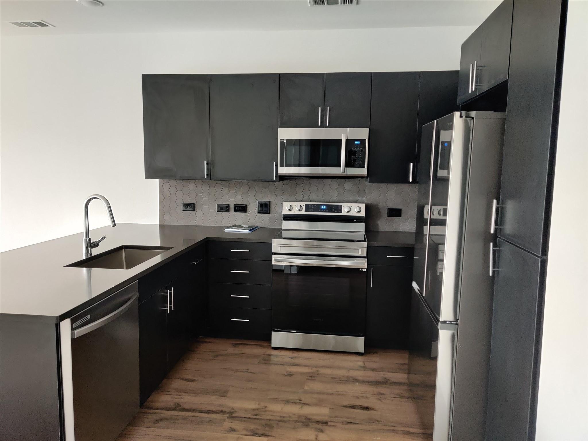 Dark cabinetry and quartz countertops pair with s