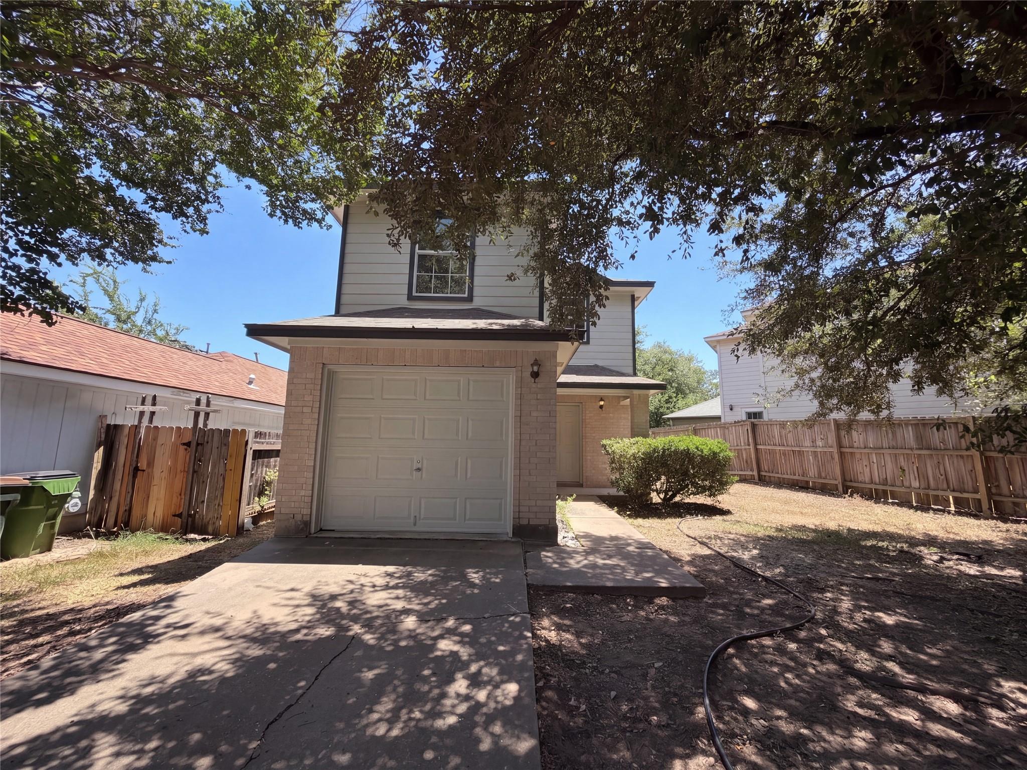 Mature trees shade a paved driveway leading to a 