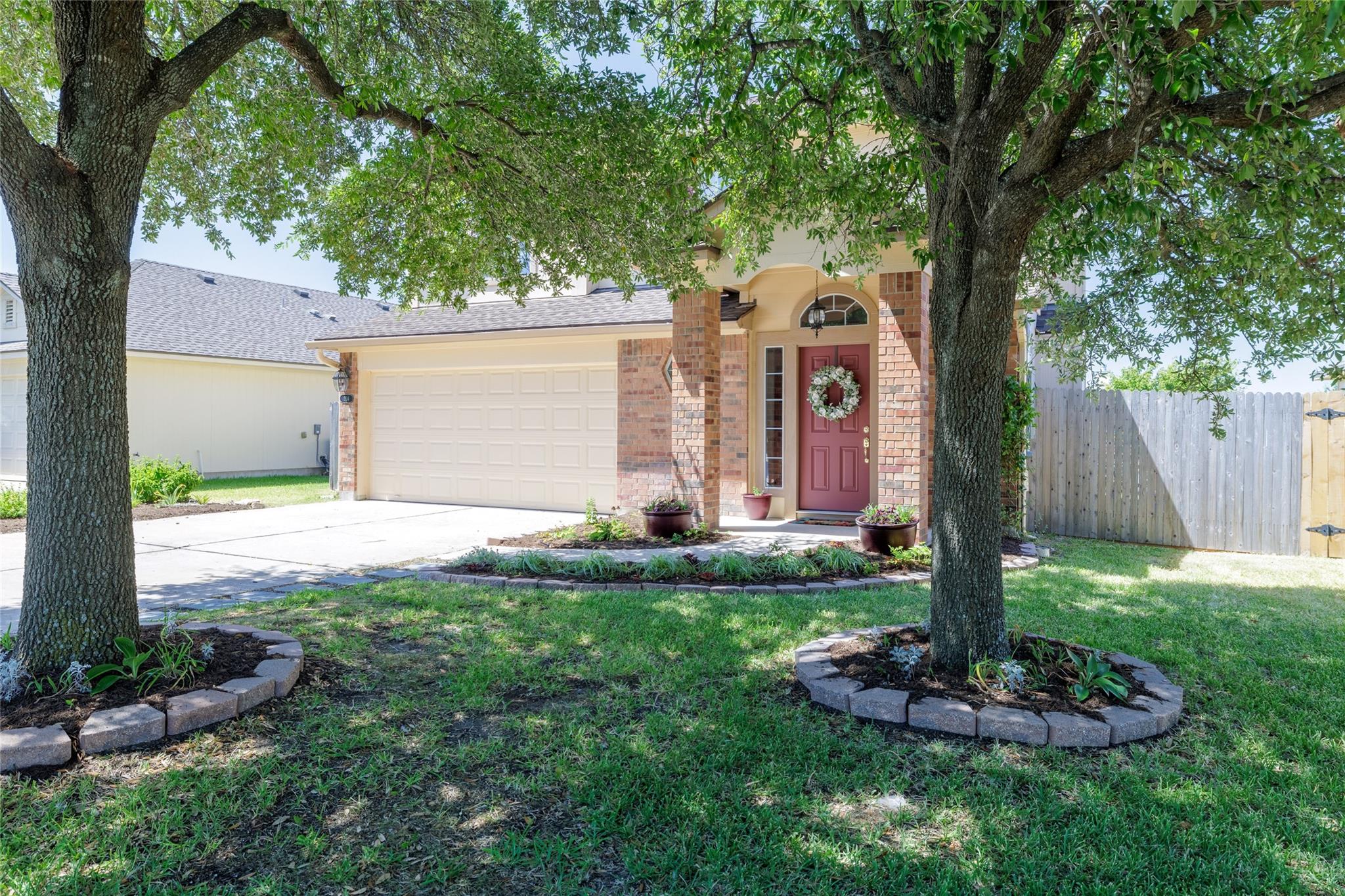 Mature shade trees and manicured garden beds fram