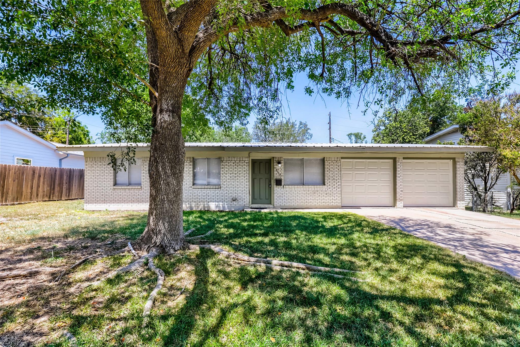 Mature shade trees frame the classic brick exteri