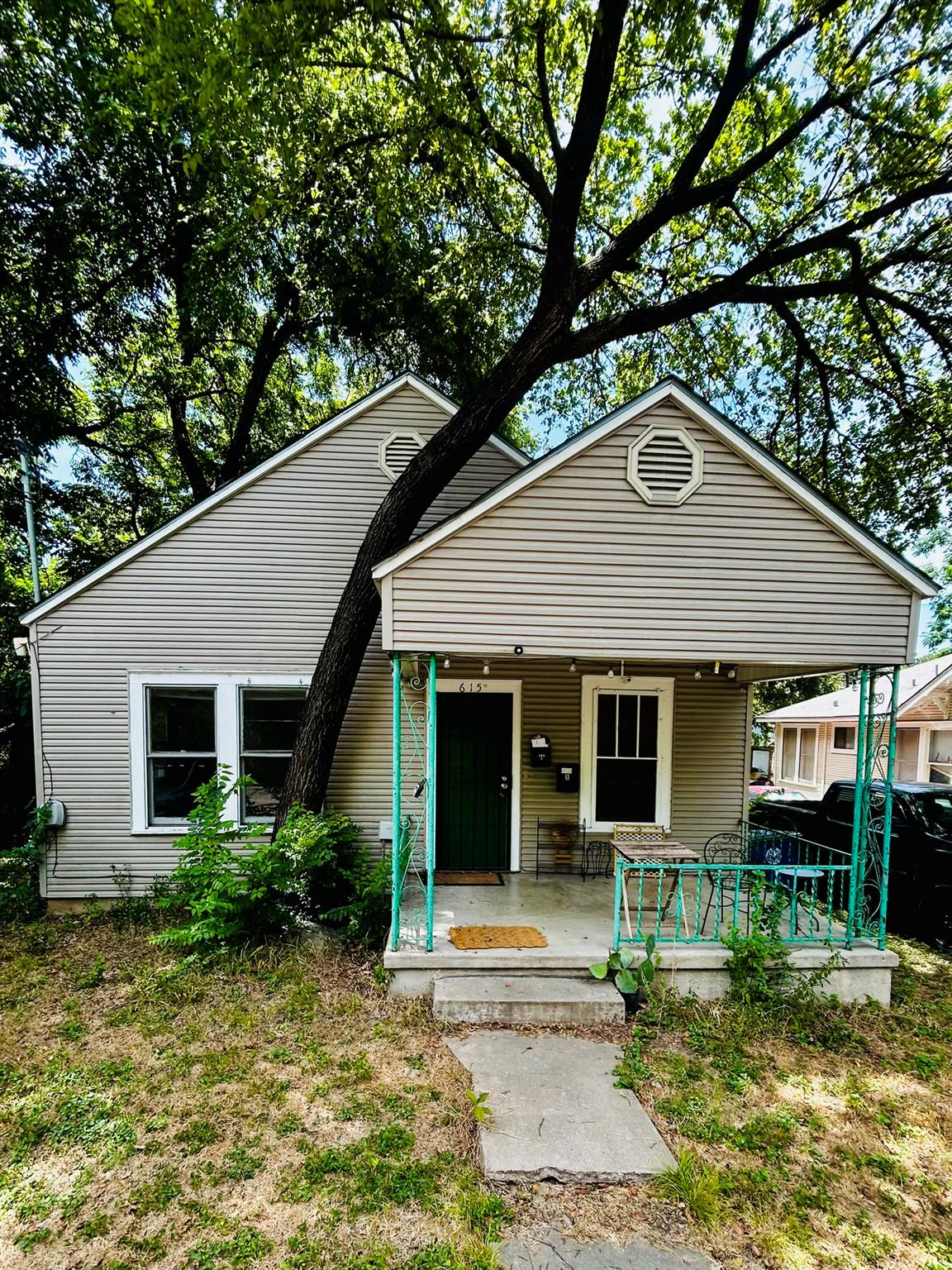 Mature shade trees frame a classic front porch wi