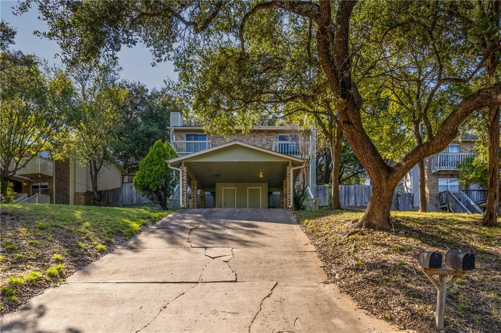 Mature trees shade a long concrete driveway leadi