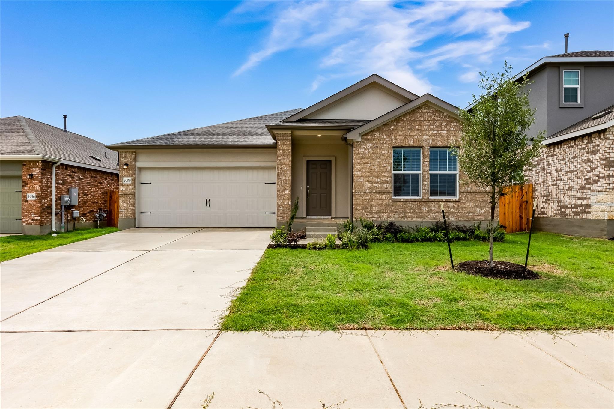 Ranch-style home with a garage, driveway, and bri