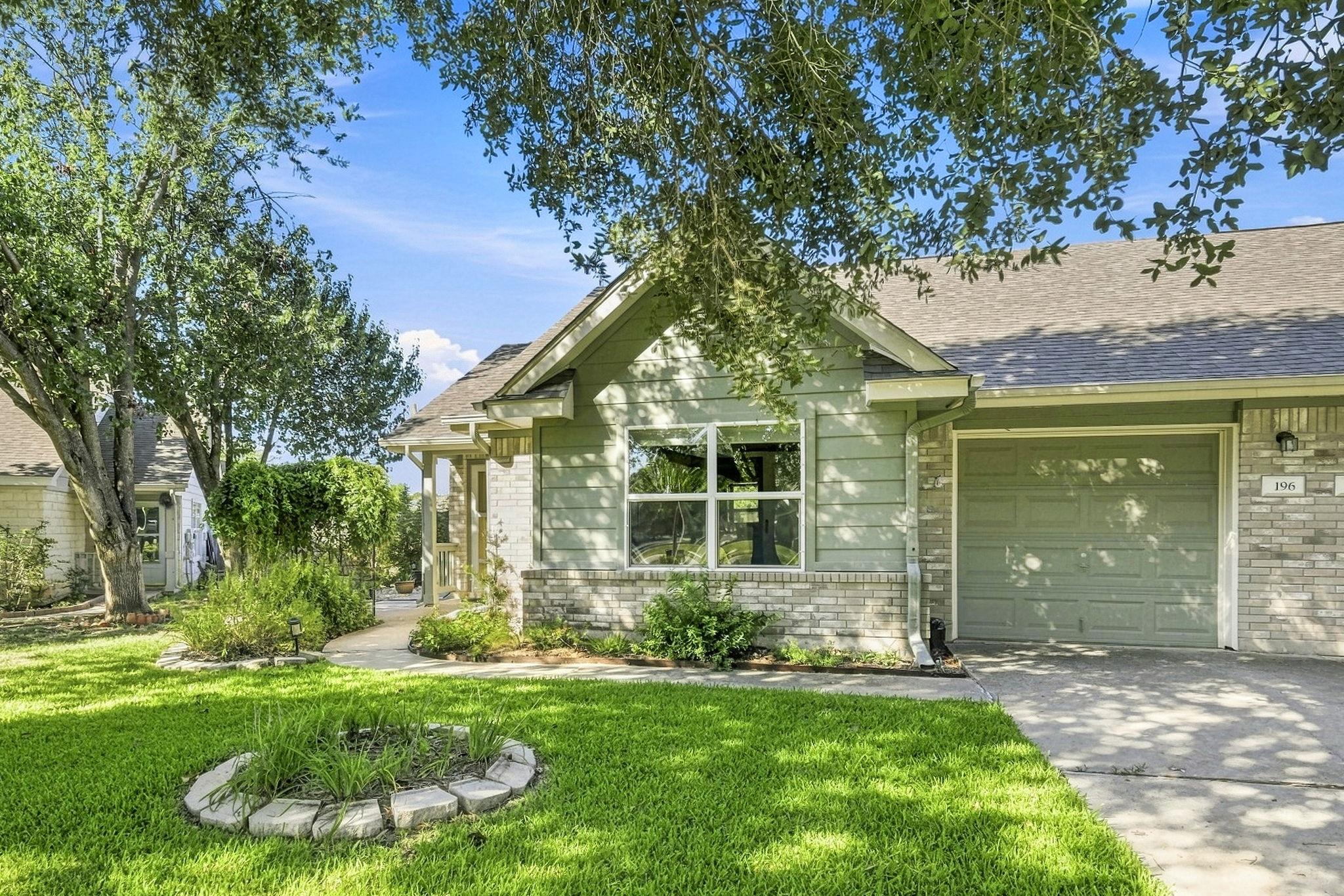 Mature trees shade a manicured front lawn leading