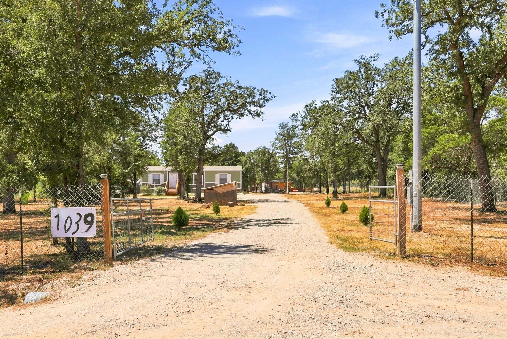 Mature trees frame a private, gated entrance lead
