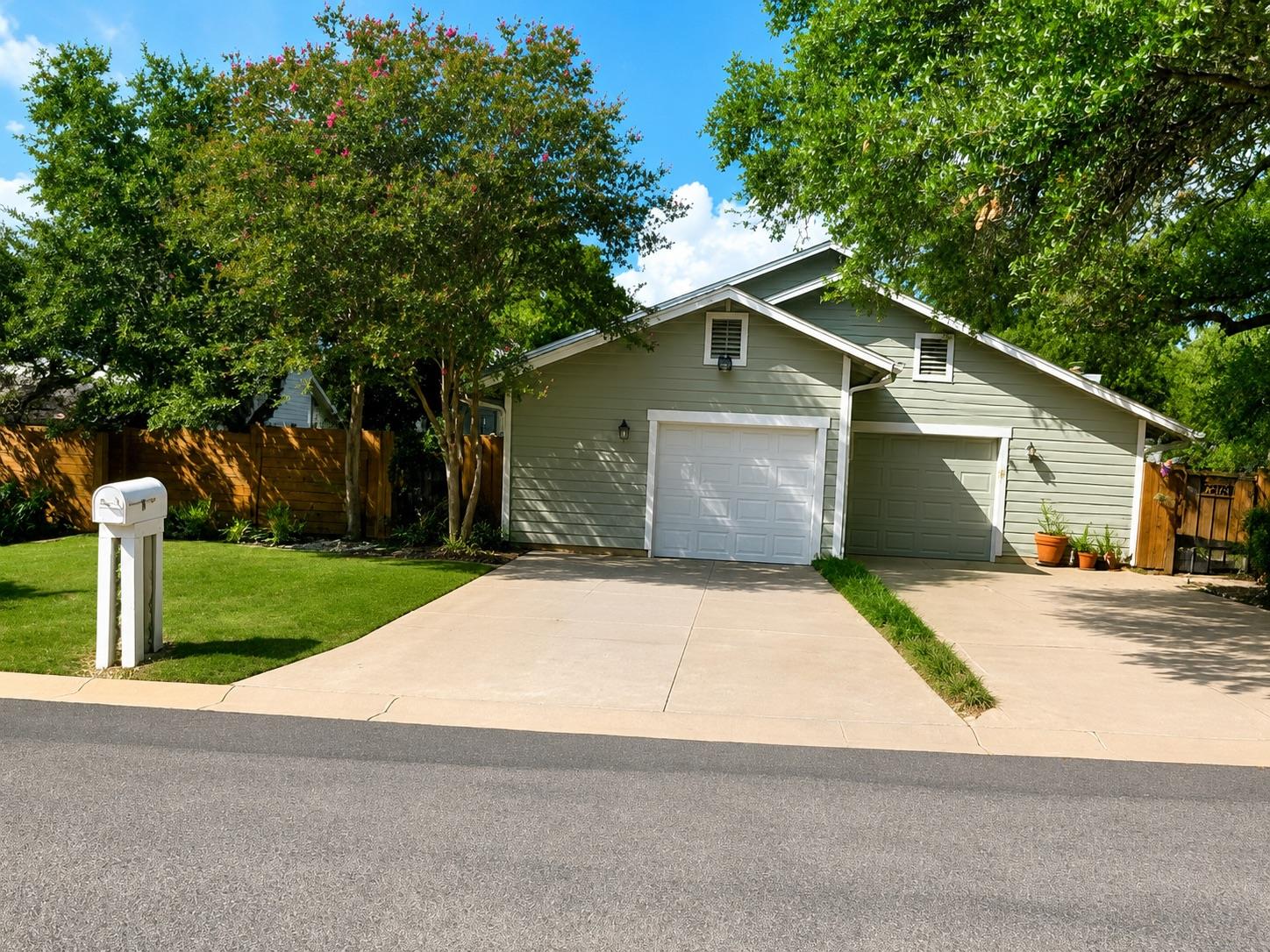 Established shade trees flank a concrete driveway