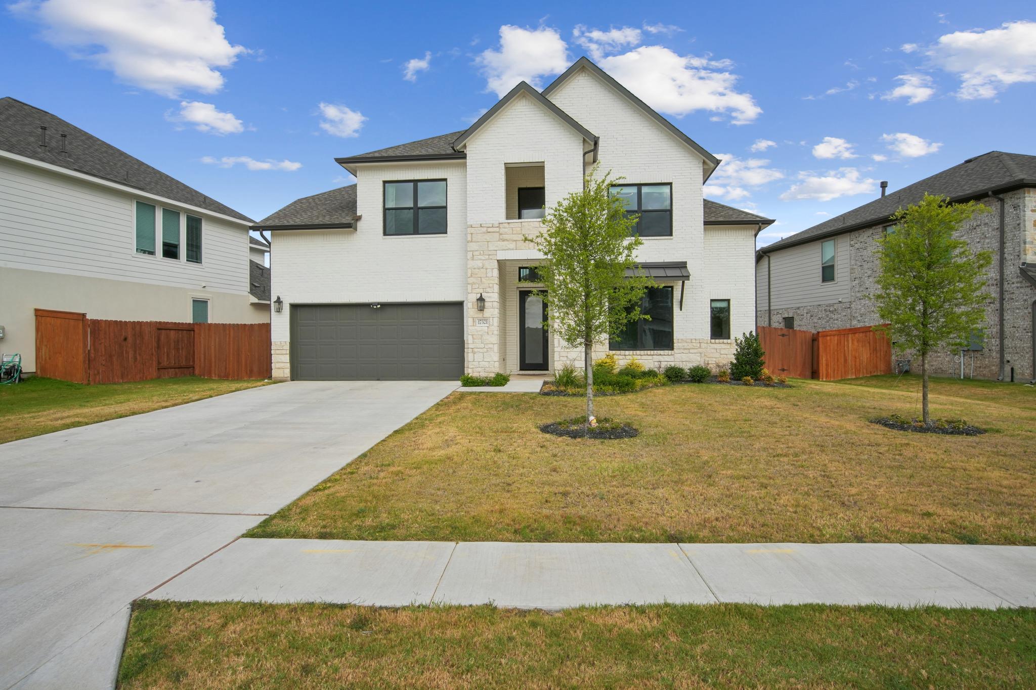 View of front of home with driveway, stone siding