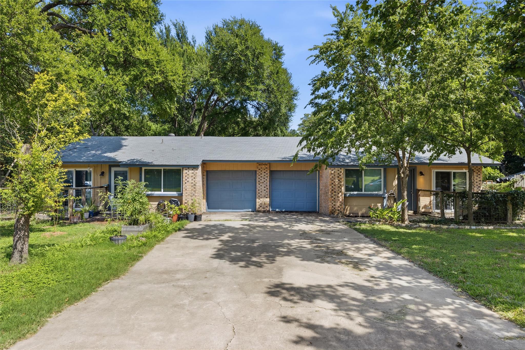 Mature trees frame a classic brick and siding dup