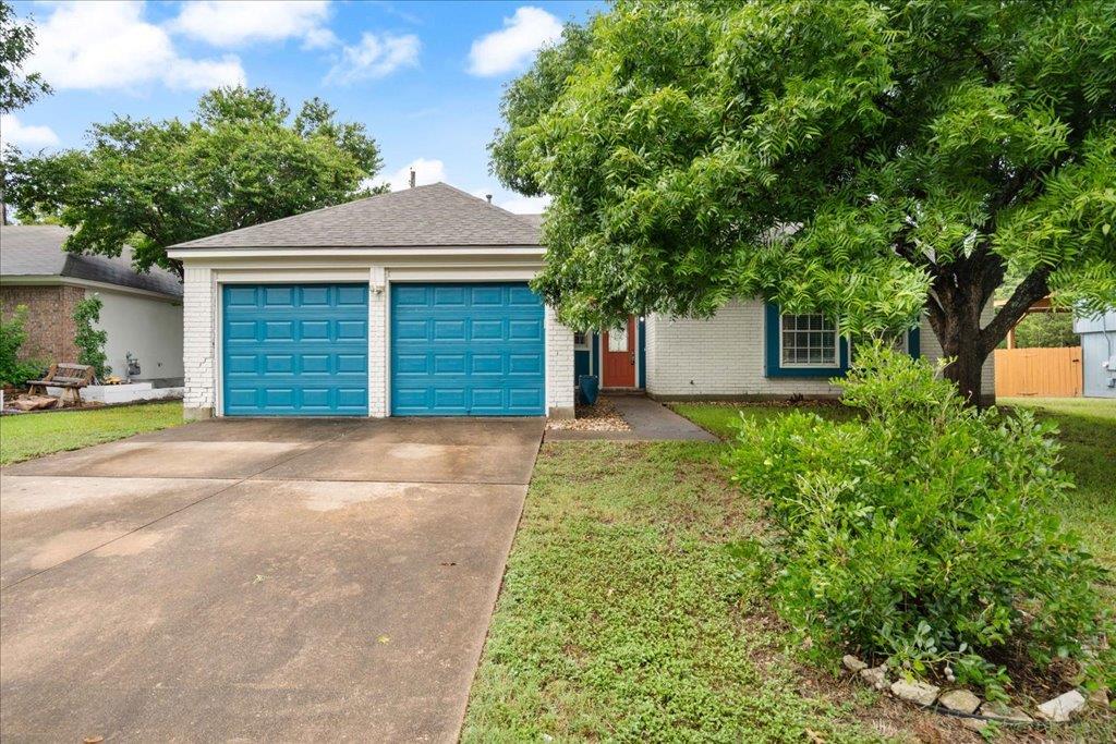 Mature shade trees and a concrete driveway lead t