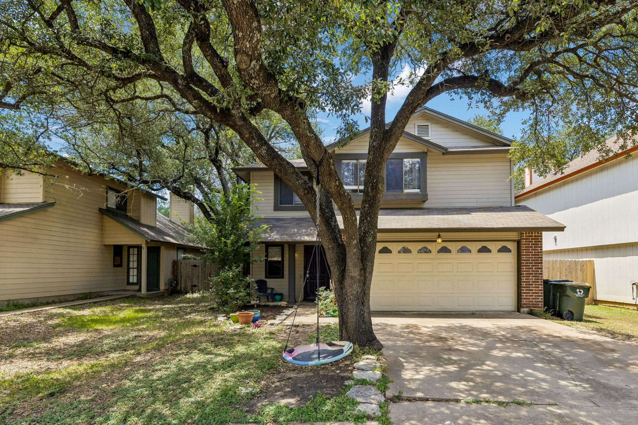 Established oak trees shade the concrete driveway