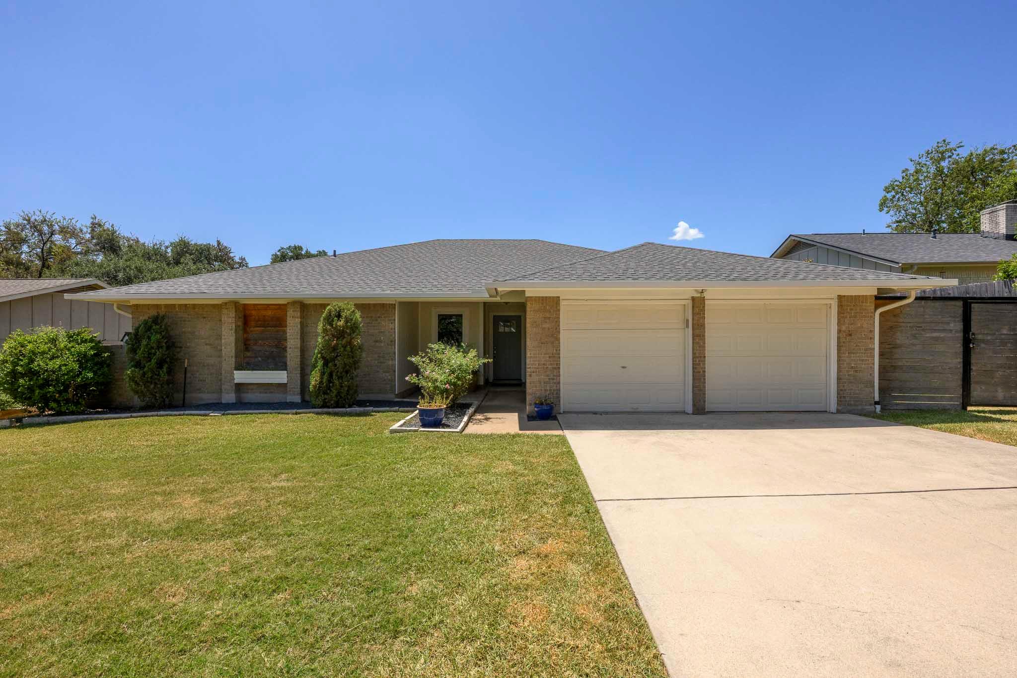 Midcentury brick ranch home displays a wide concr