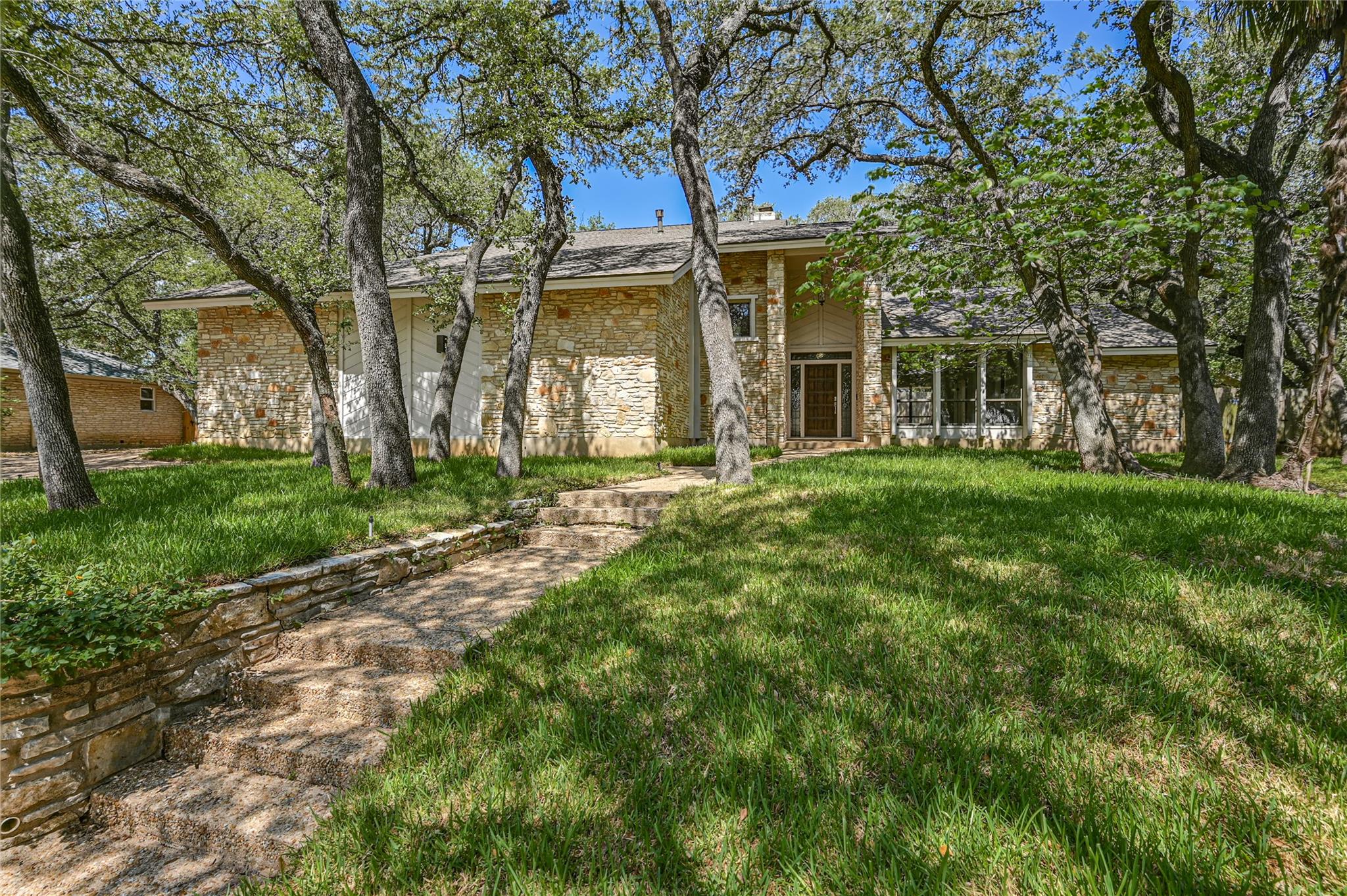 Mature shade trees and stone steps lead toward th
