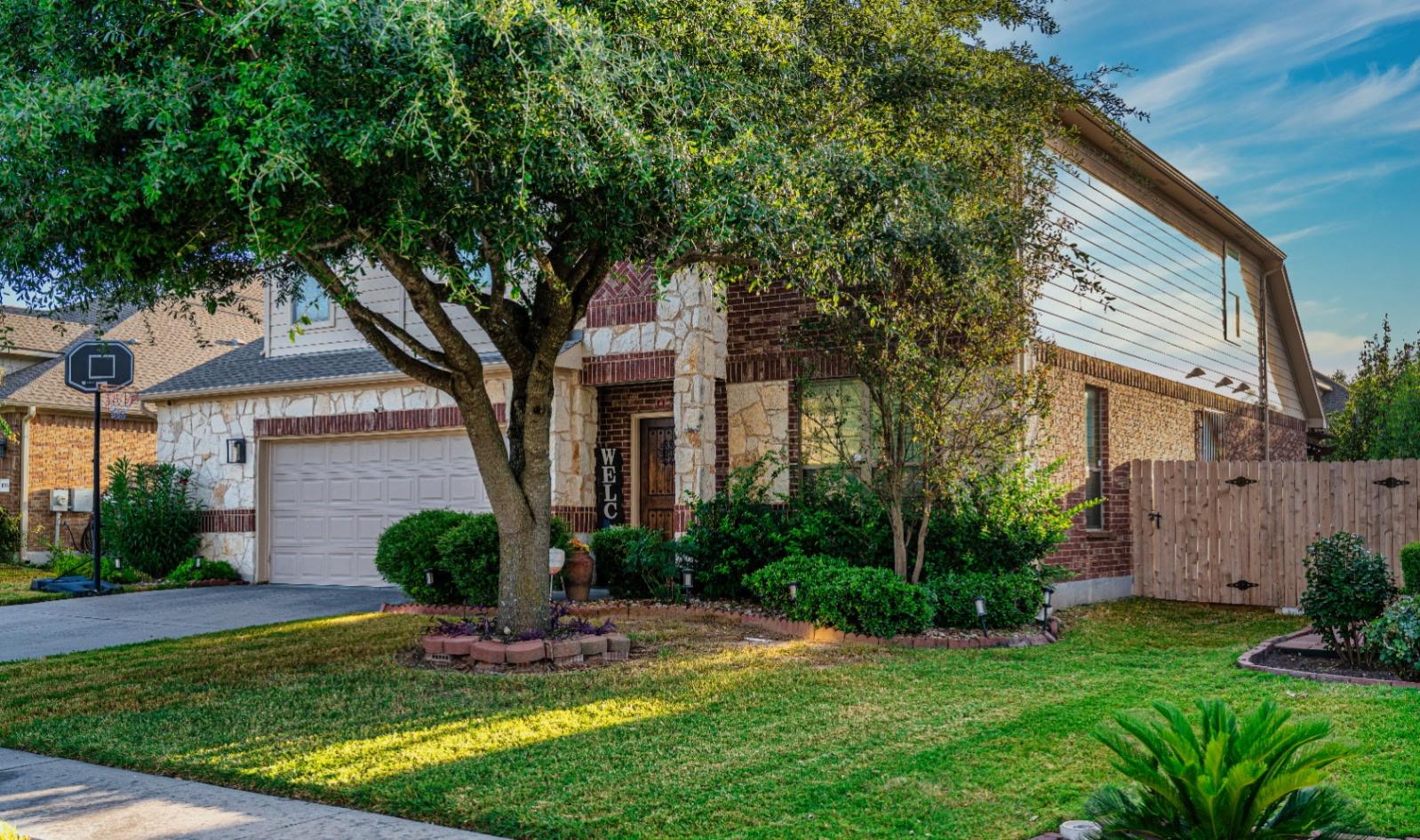 Mature trees shade a classic brick and stone faca