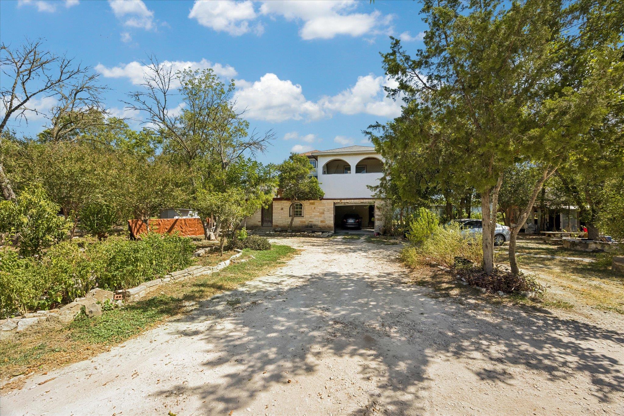 Mature trees frame the rustic exterior and stone 