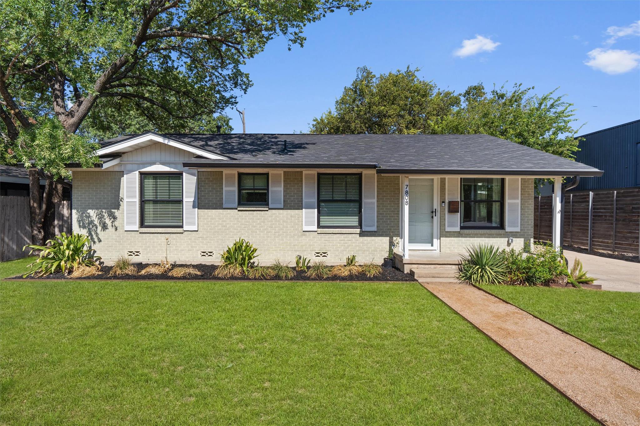 Mature trees shade a classic single-story brick f