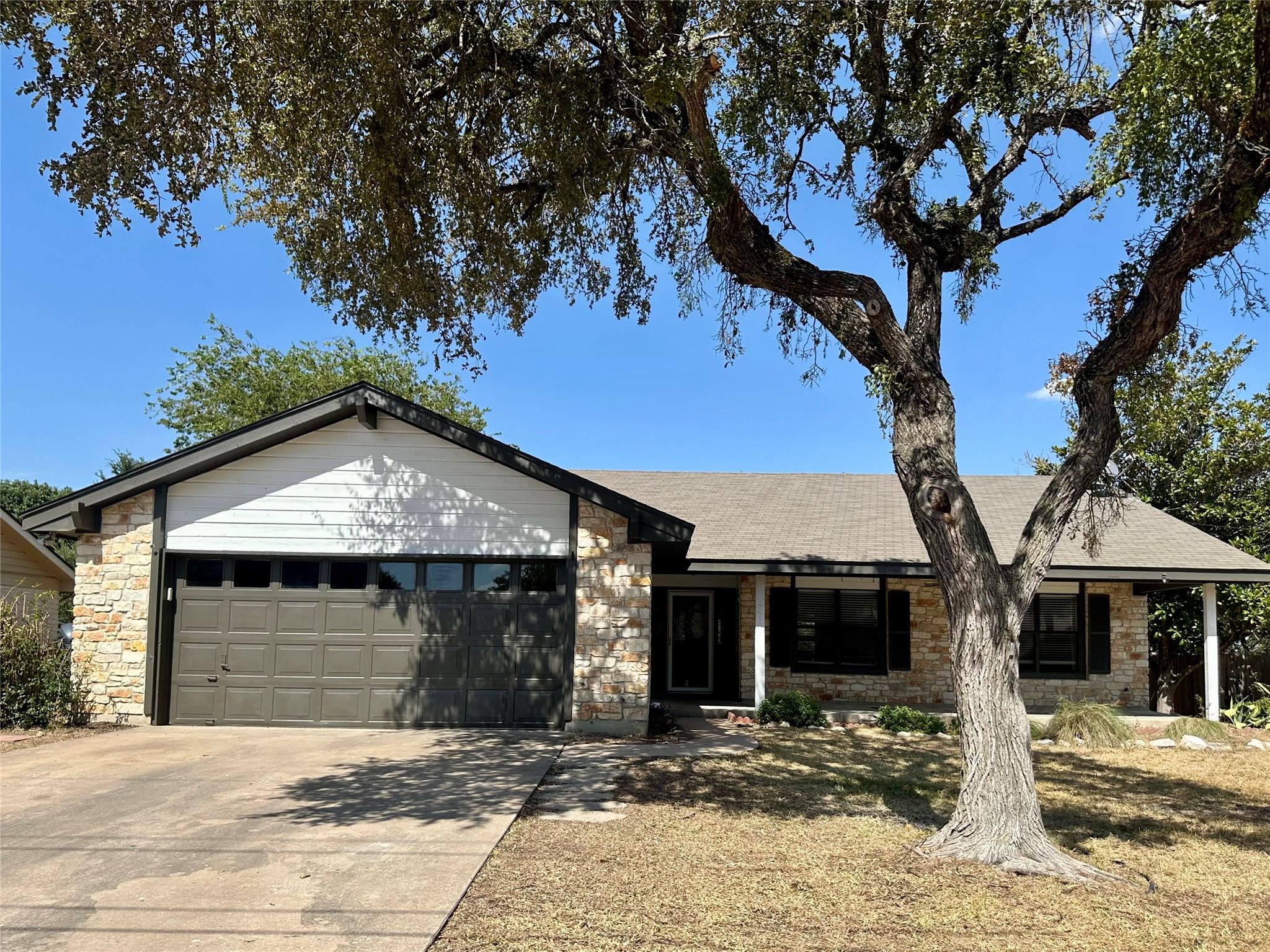 Mature trees shade a classic single-story stone e