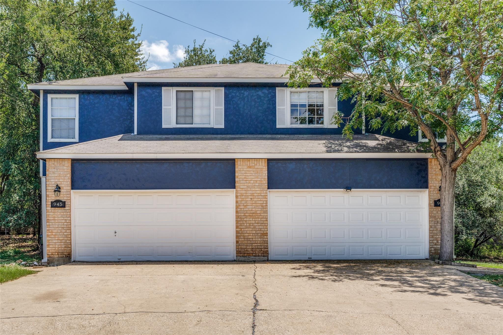 A spacious driveway leads to dual garage doors fr