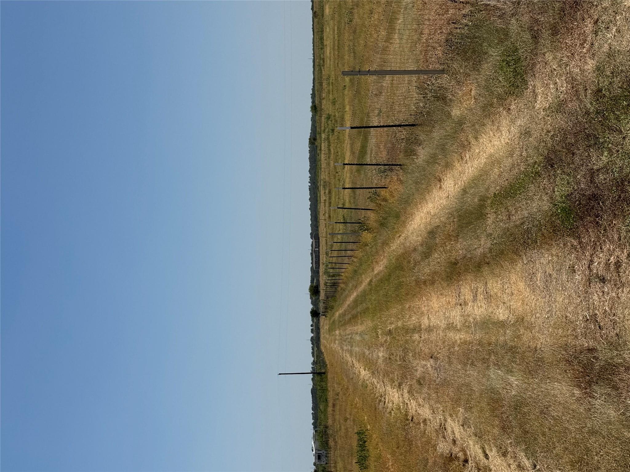 A long grassy driveway runs alongside fenced acre