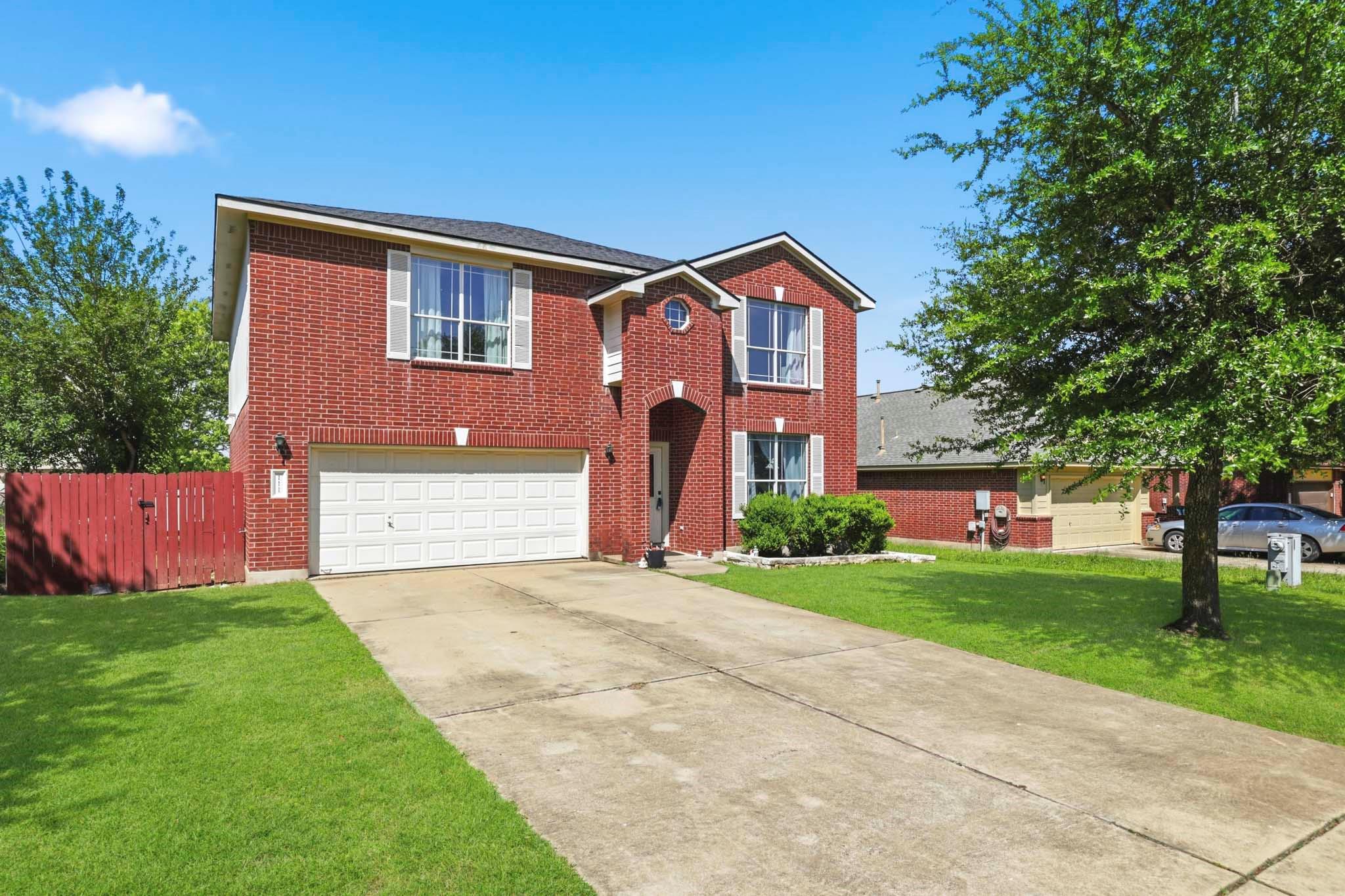 A long concrete driveway leads to a two-story bri