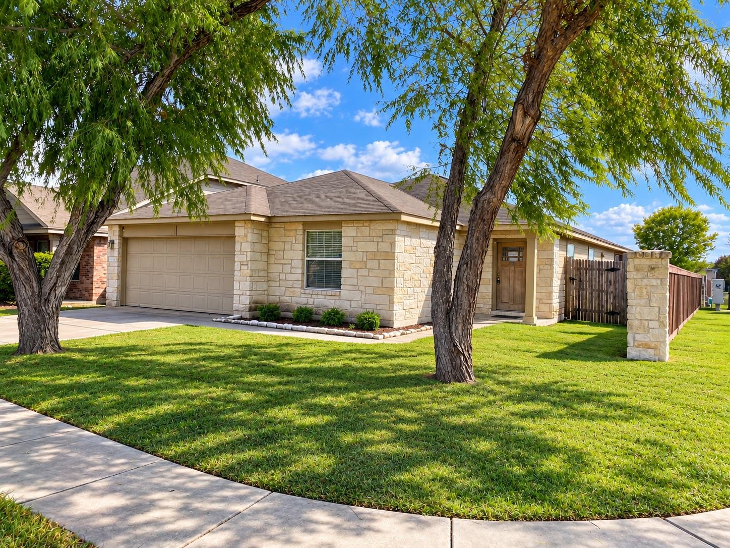 Mature trees shade a manicured front lawn leading