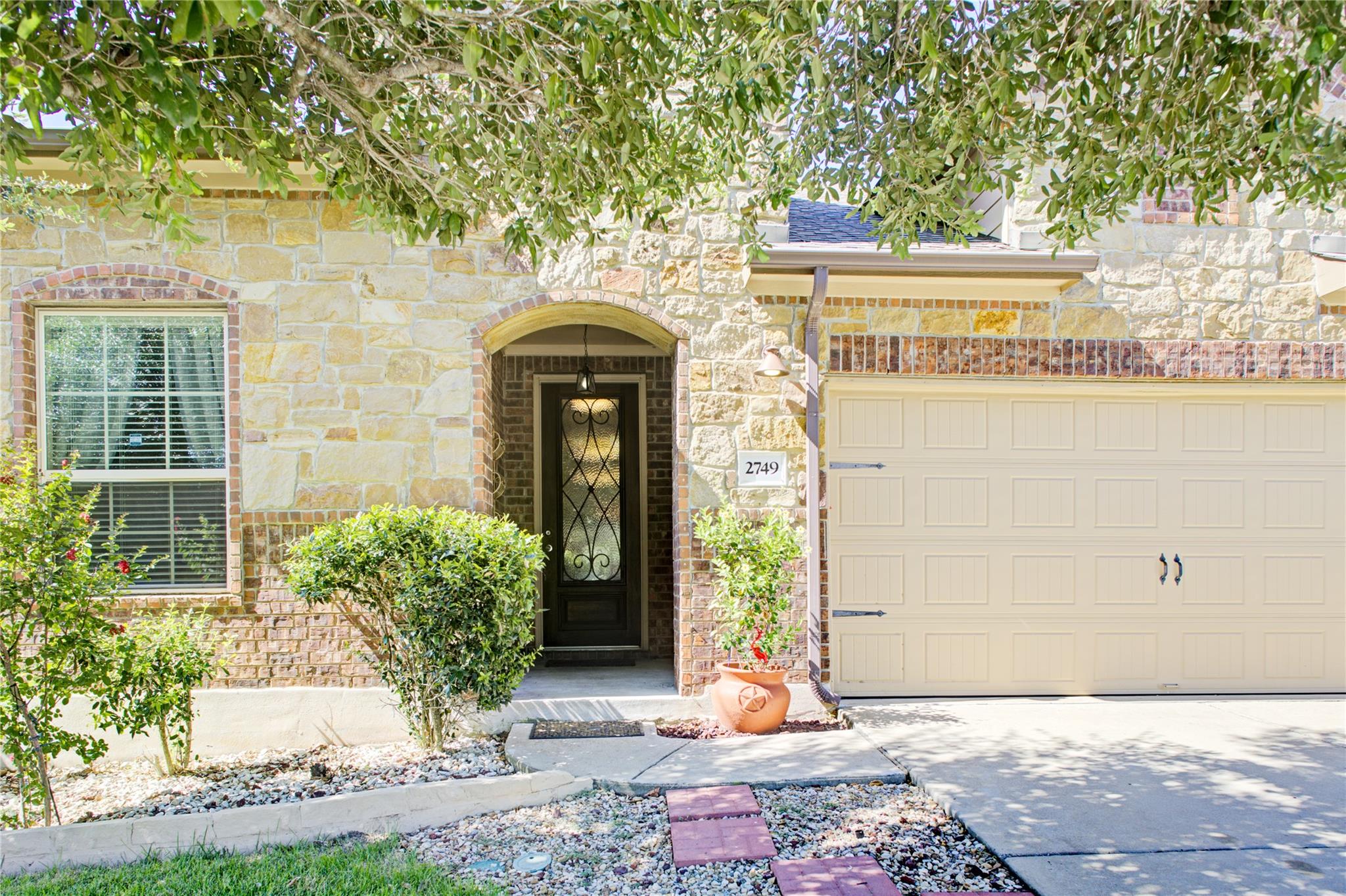 A natural stone facade pairs with an arched entry