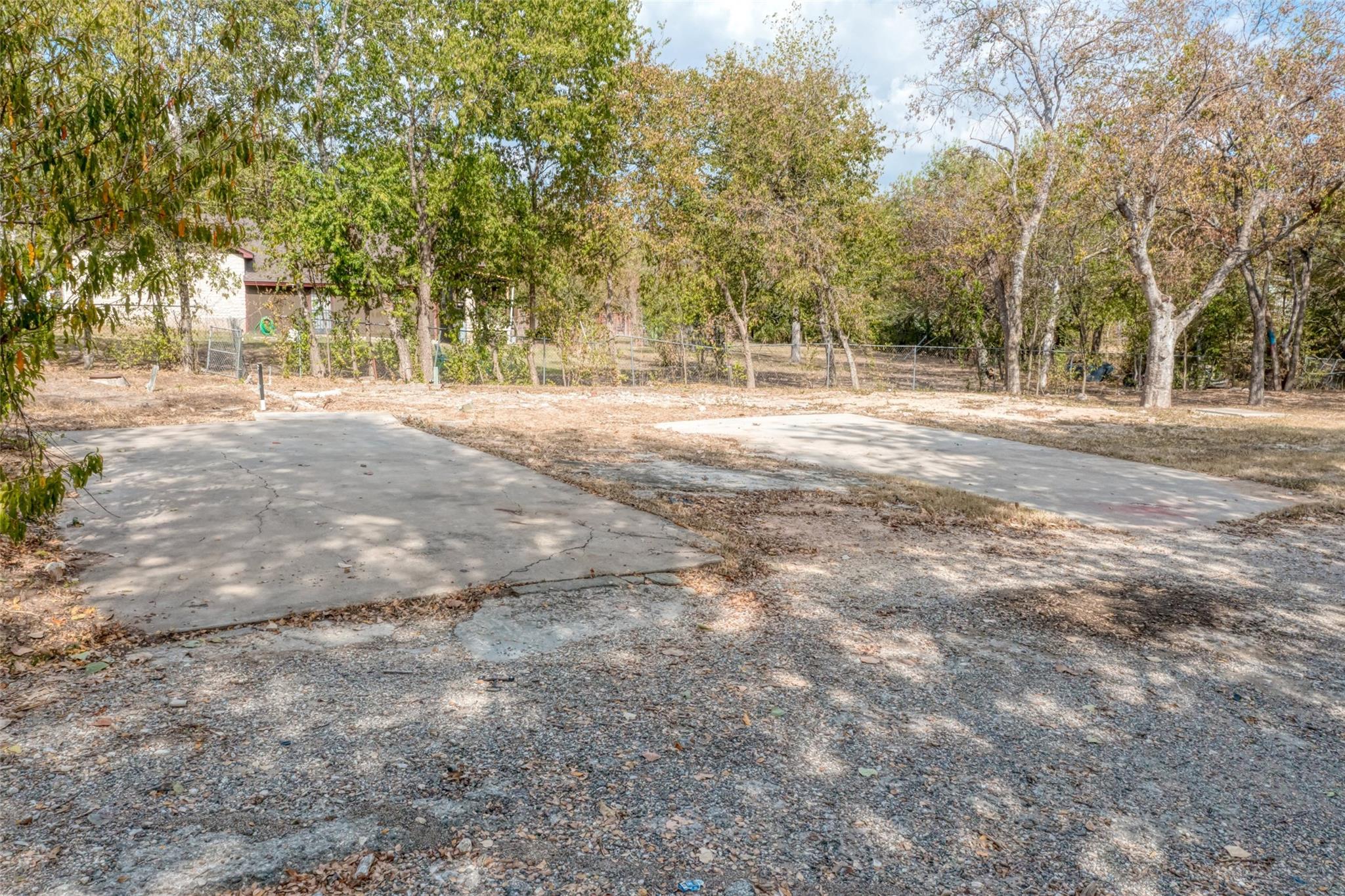 Mature trees frame concrete pads on a spacious lo