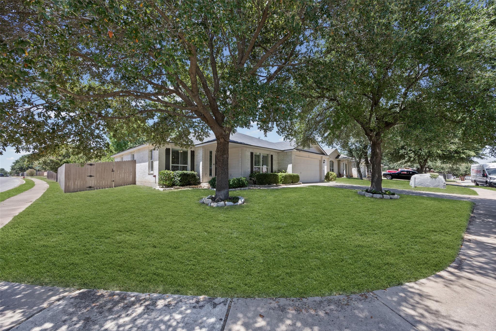 Mature shade trees frame the manicured lawn of th