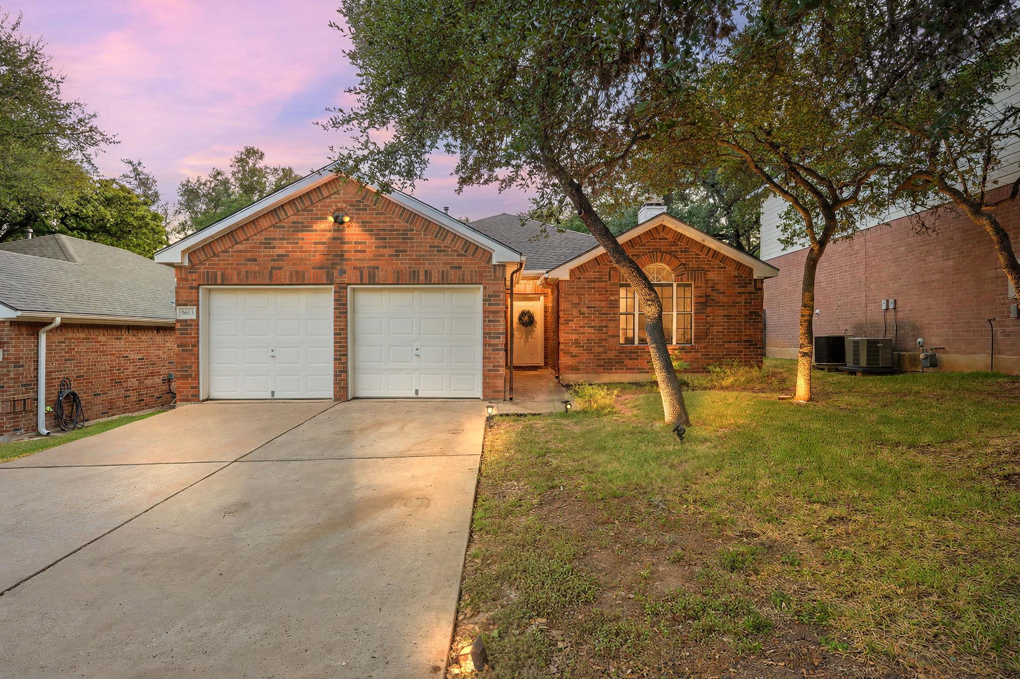 Mature trees shade a classic brick exterior featu
