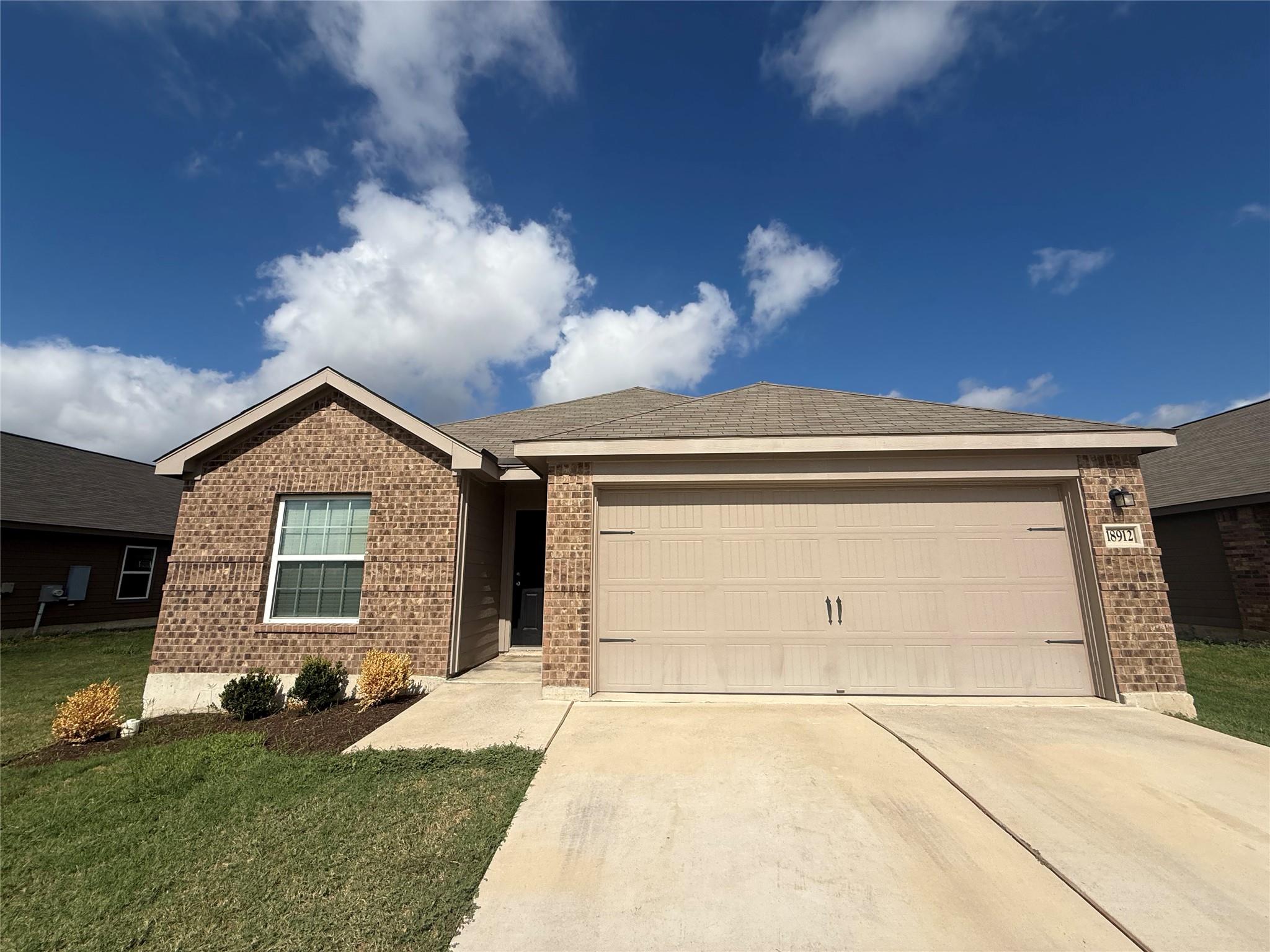Brick siding pairs with a neat concrete driveway 