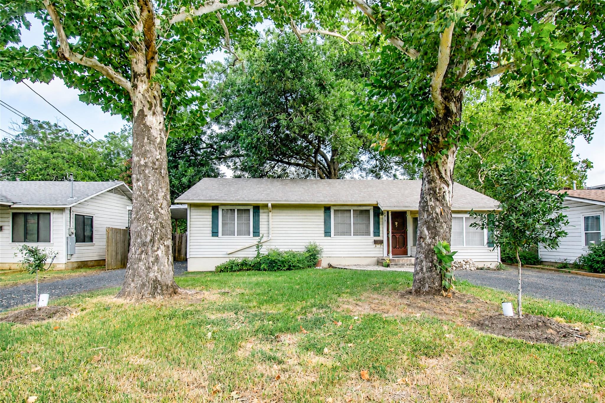 Mature trees shade a classic single-story home wi