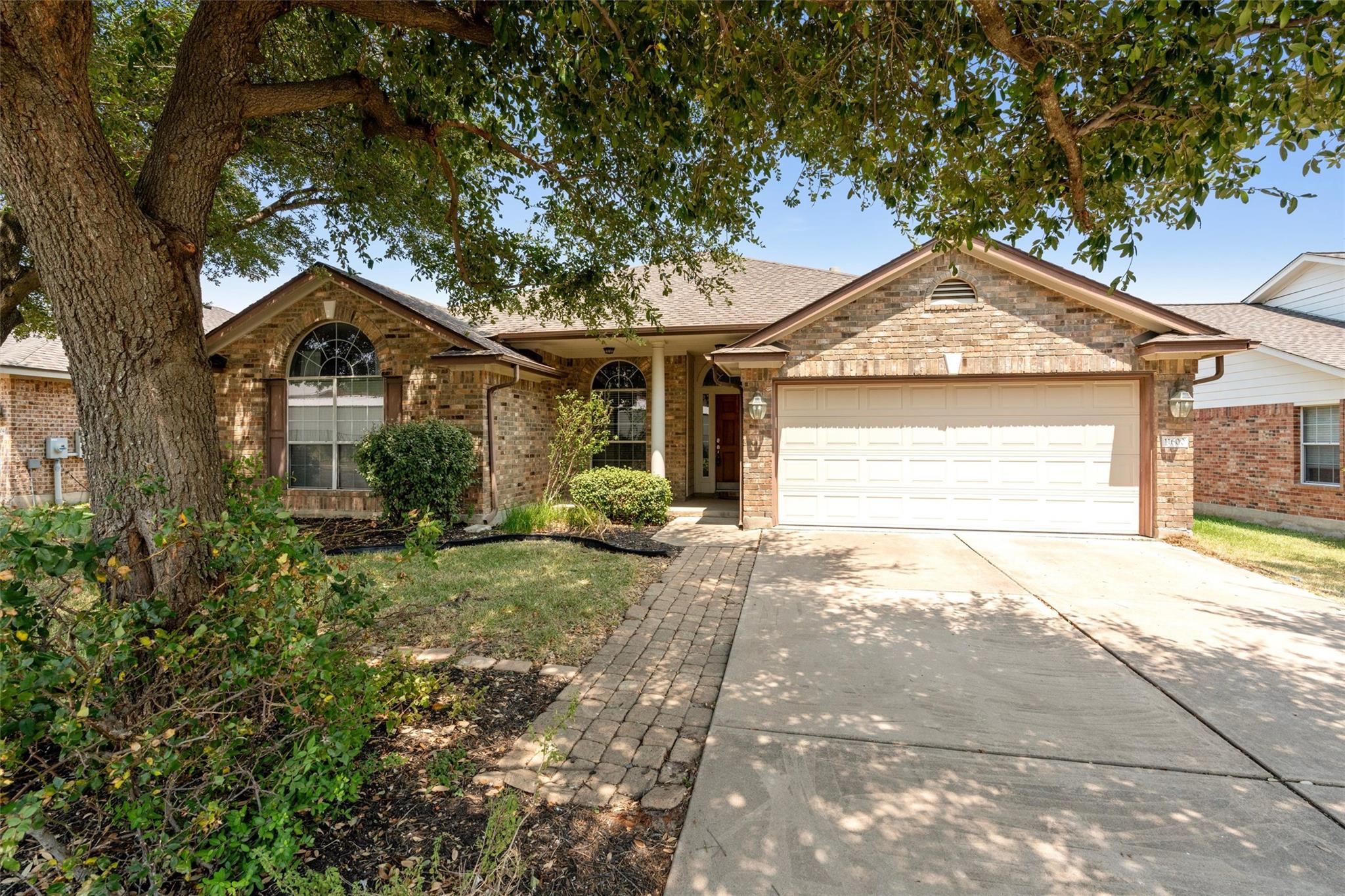 Mature trees shade a classic brick exterior compl