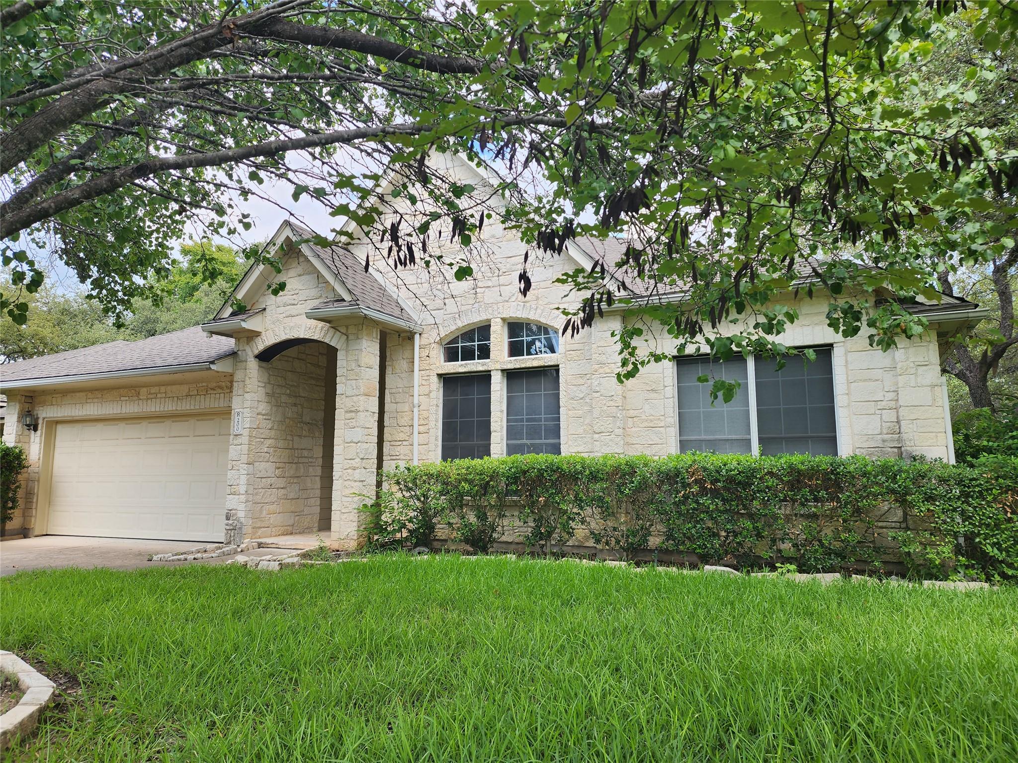 Mature trees shade a classic stone exterior featu