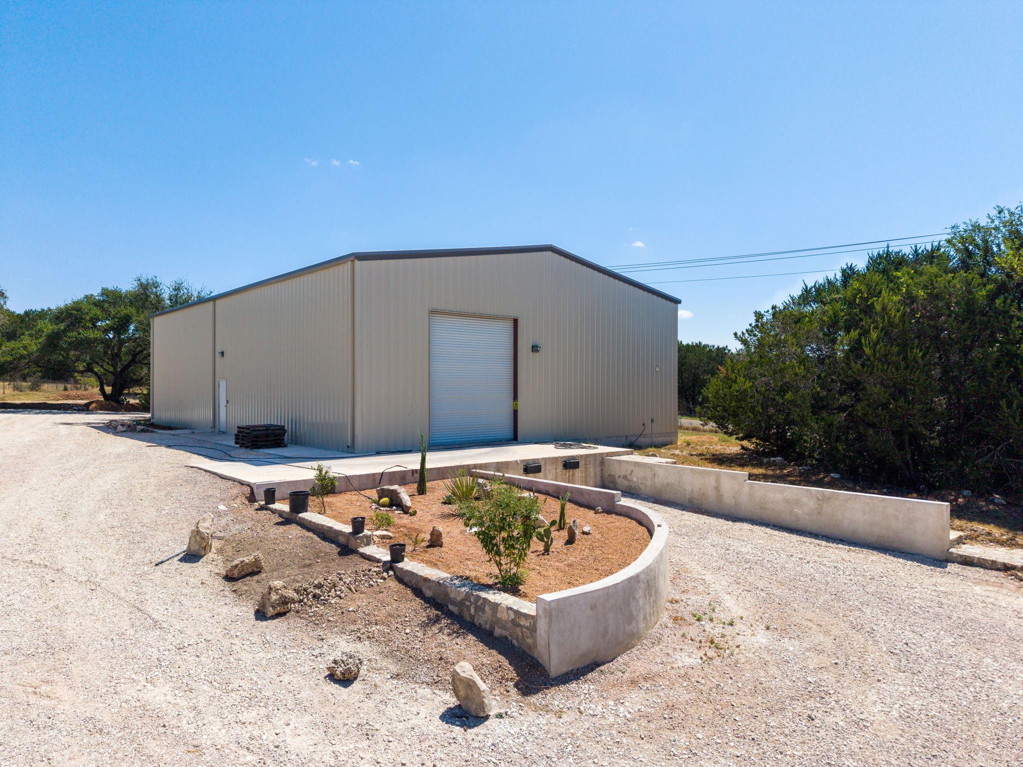 A detached metal outbuilding features a roll-up b