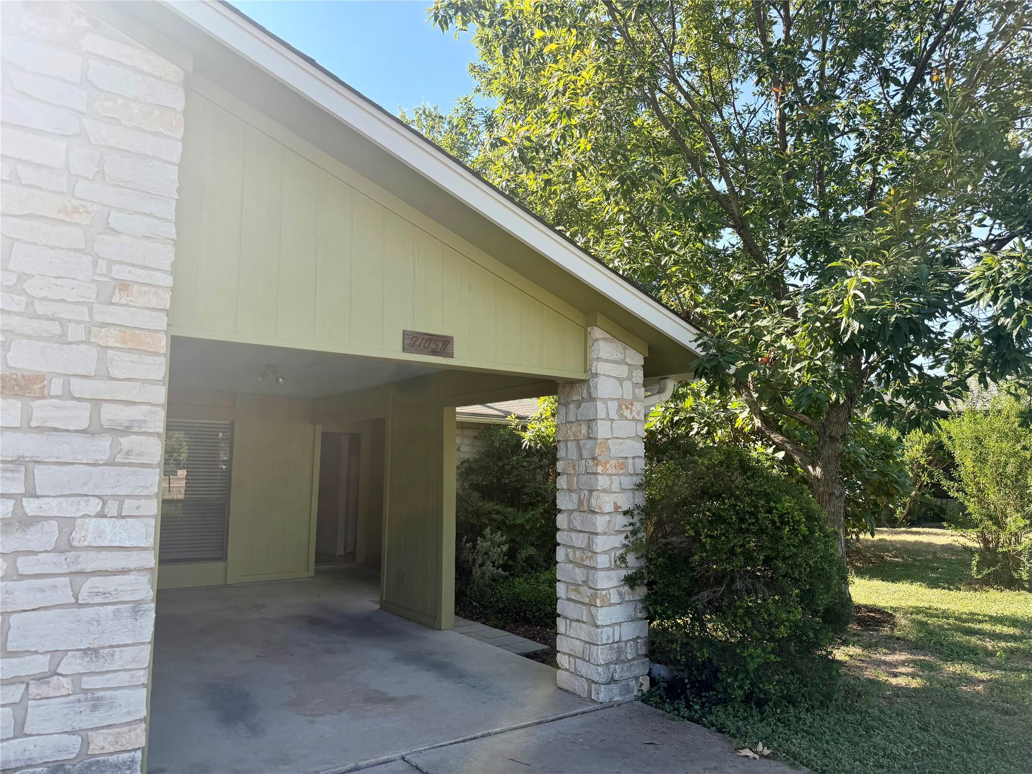 Natural stone columns frame a covered carport alo