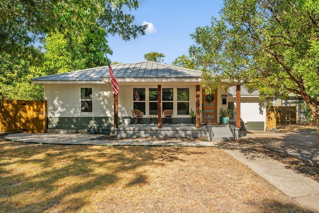 Mature trees shade a welcoming front porch with c