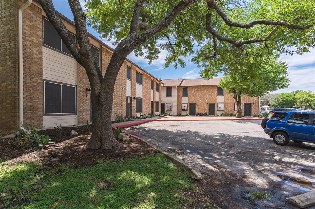 Mature shade trees frame the classic brick and si