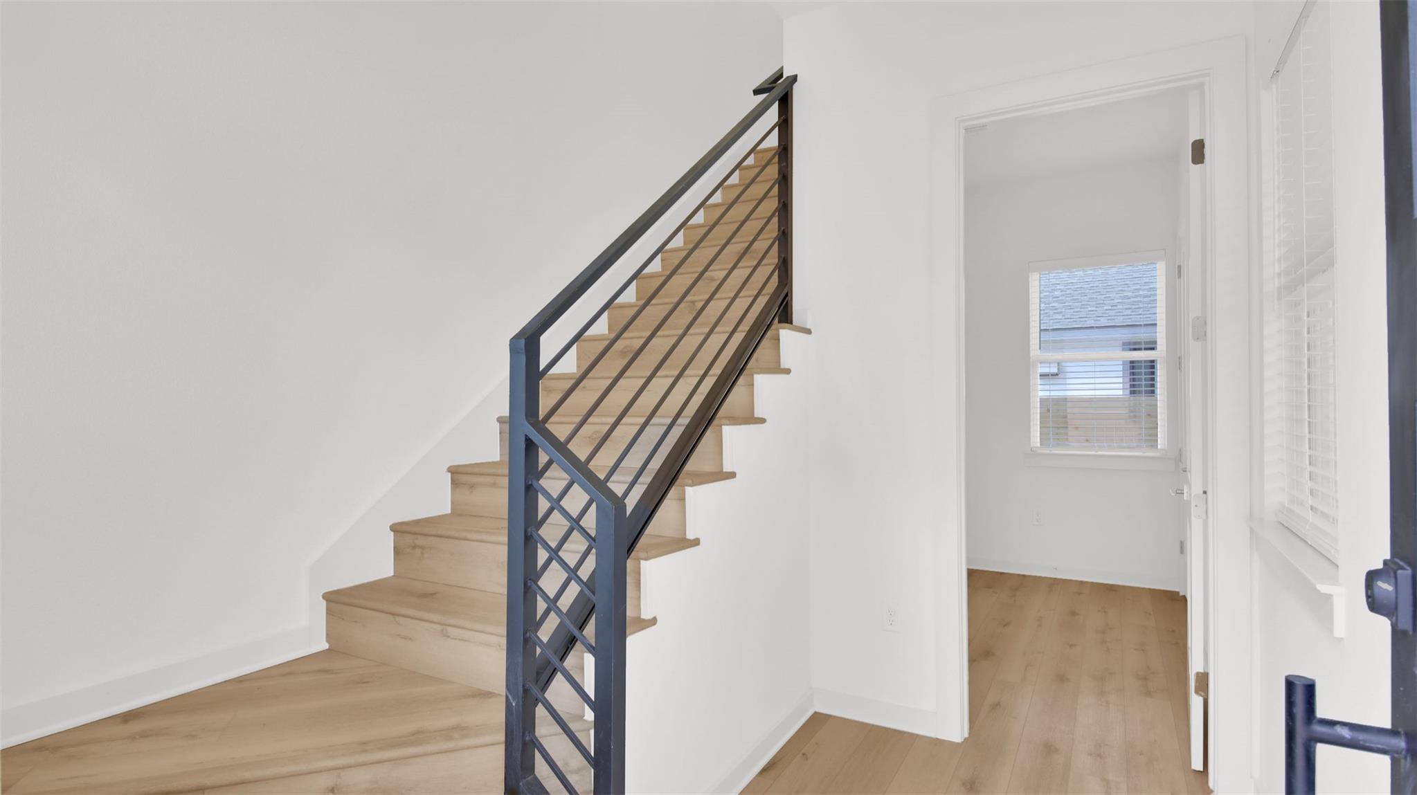Crisp white walls frame a modern wooden staircase